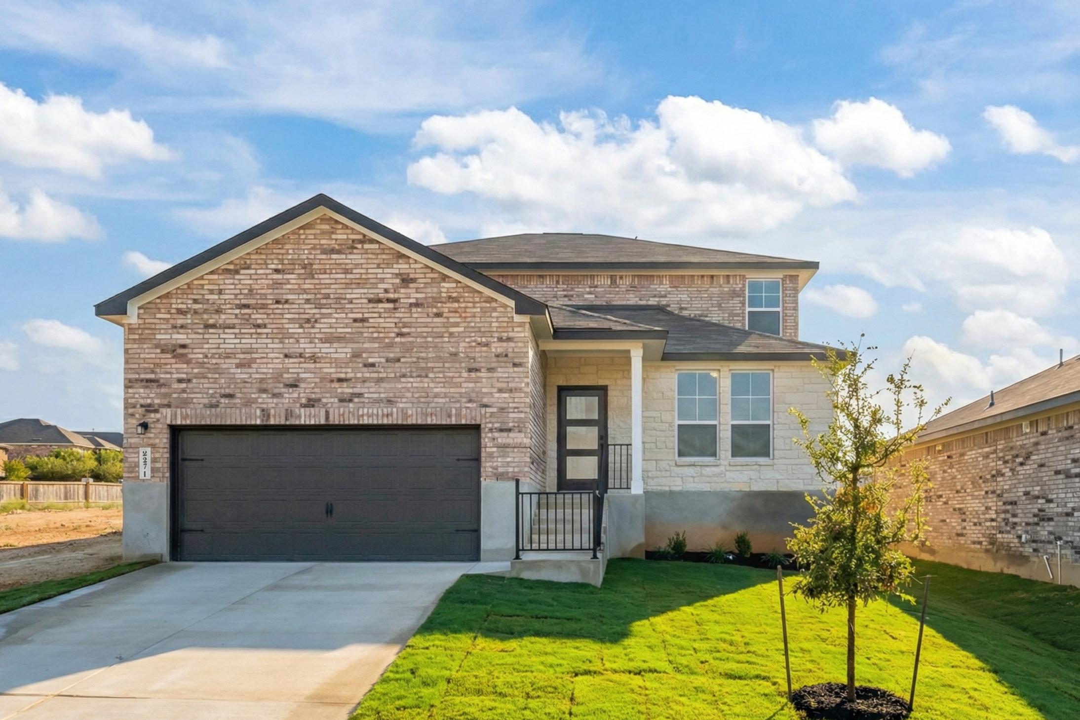 Modern brick ranch home exterior at Comanche Ridge in San Antonio Texas with garage driveway and landscaped front yard
