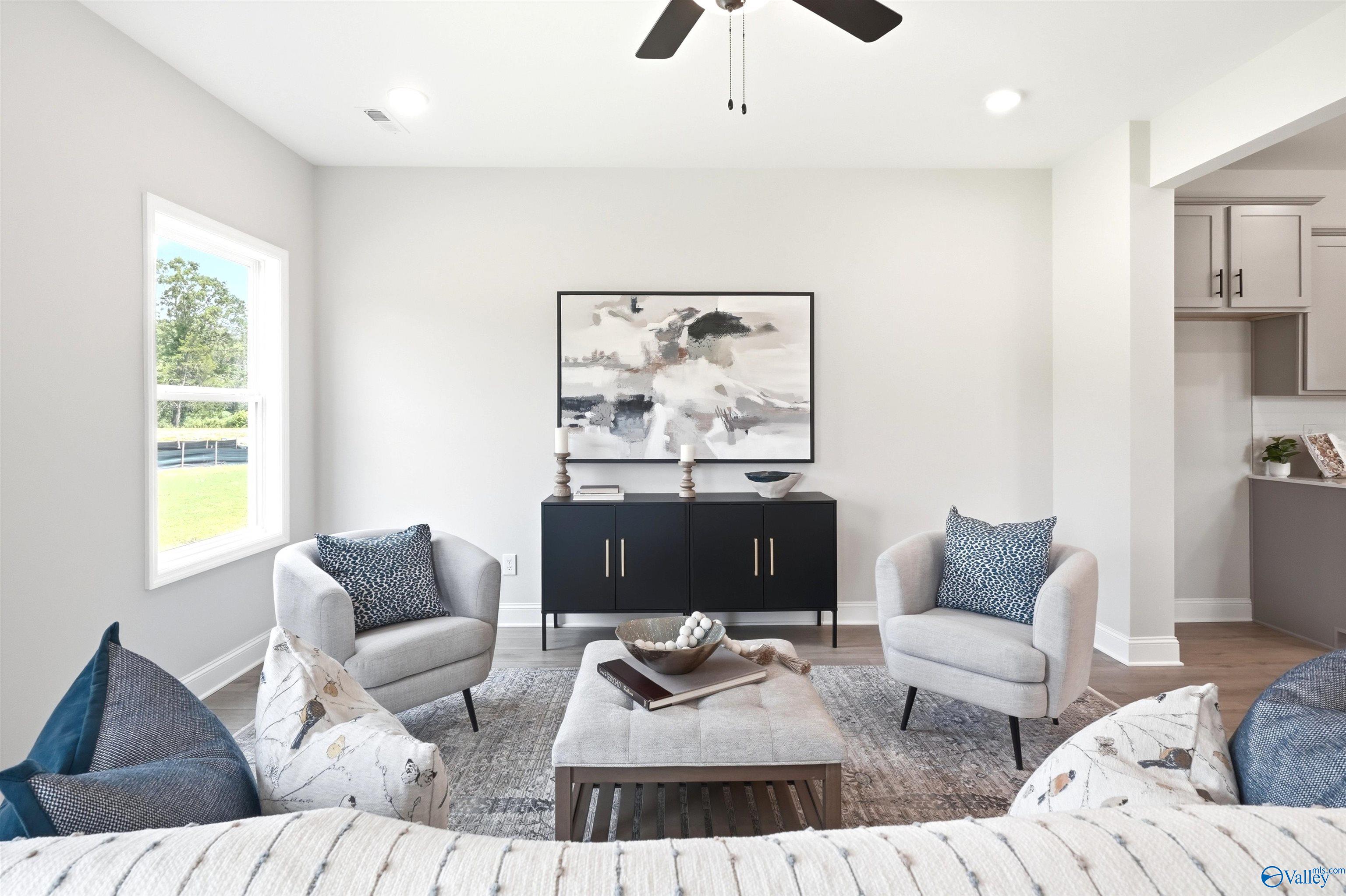 Bright living room with gray armchairs, black console, and abstract art in The Russell A floor plan by Davidson Homes, Huntsville, Alabama