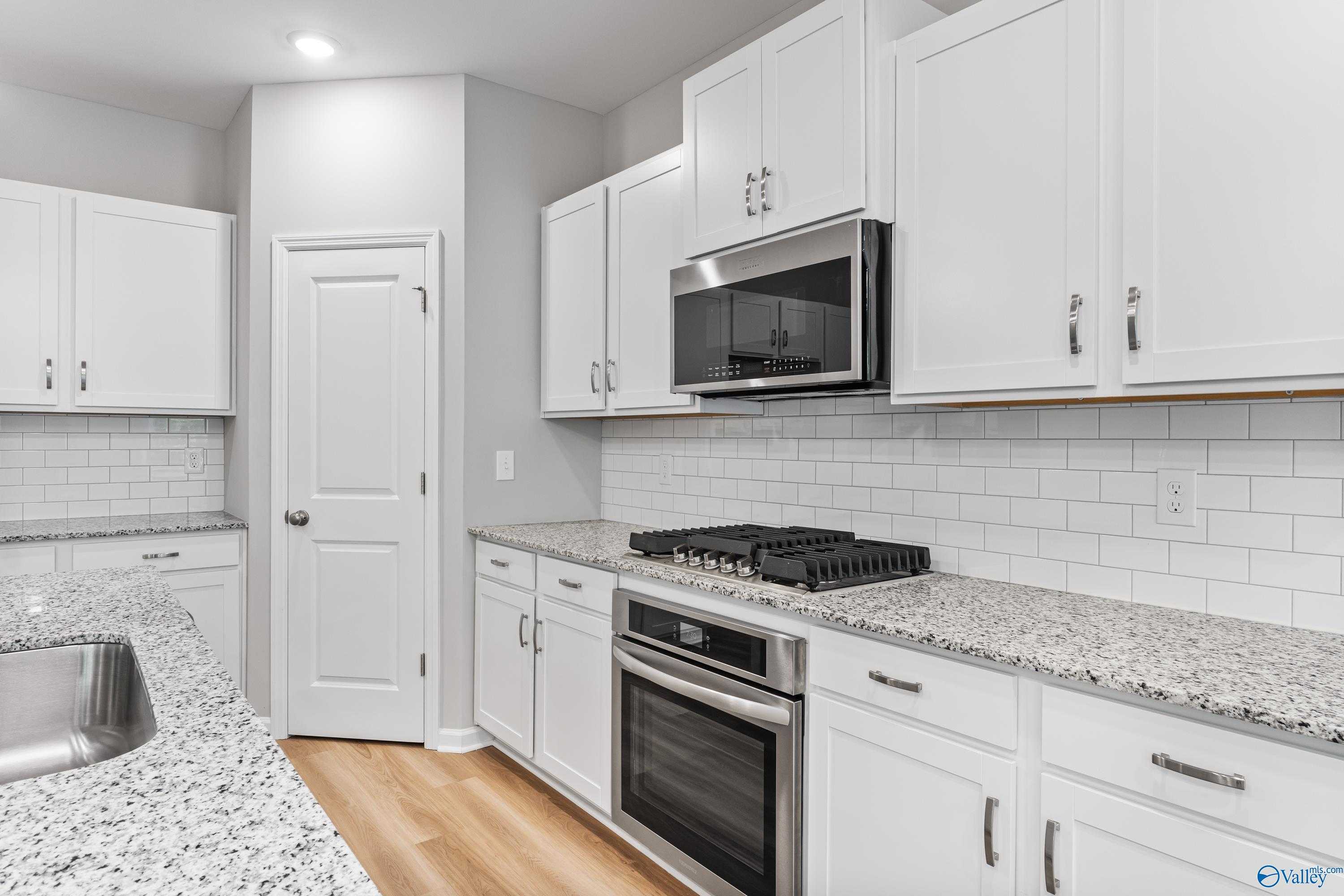 Modern white kitchen with granite countertops, stainless appliances, subway tile backsplash in Davidson Homes The Phoenix, Hazel Green AL