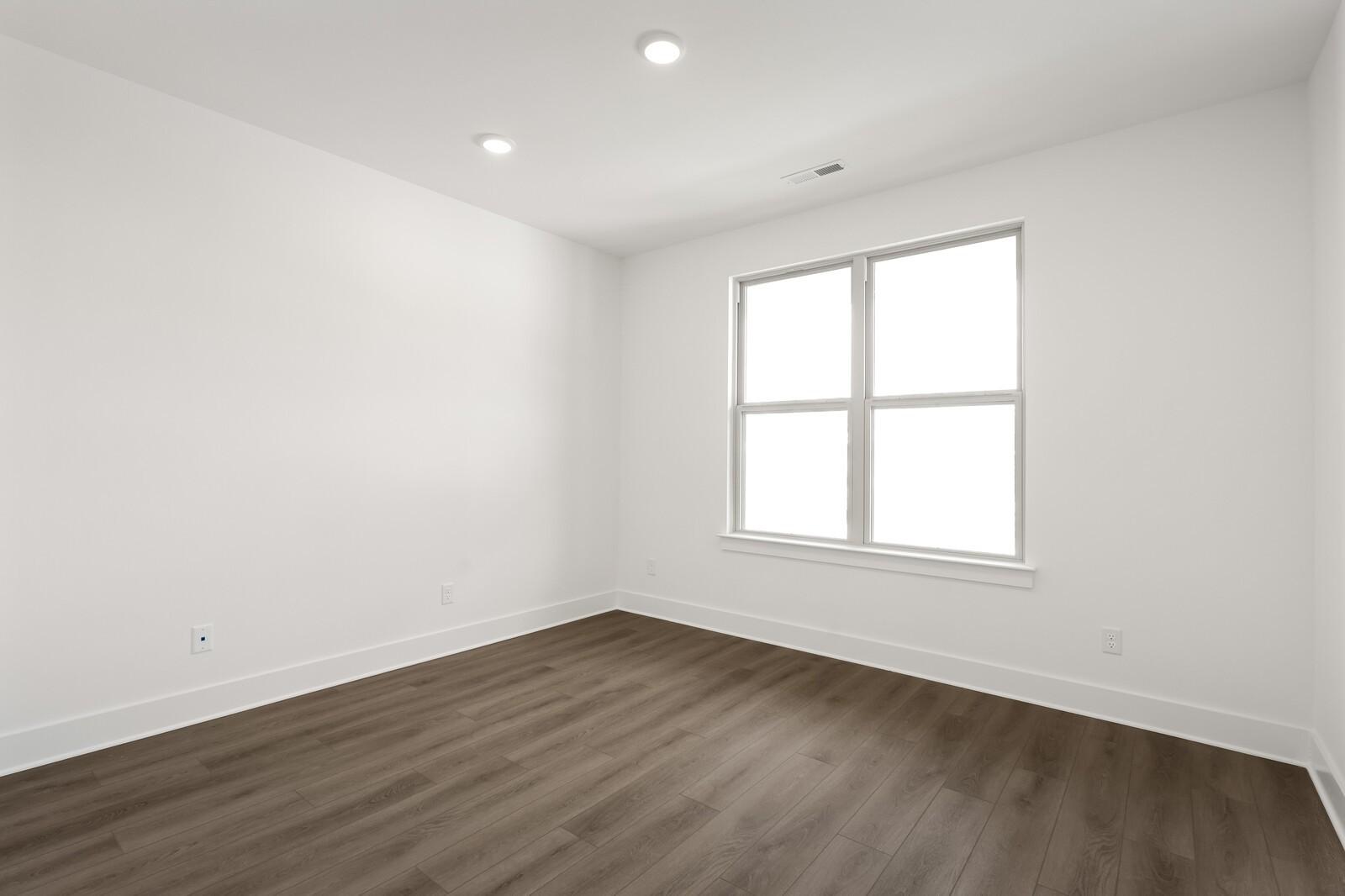 Bright, spacious bedroom with neutral walls and wood-look flooring in The Ridgeport C floor plan at Woods Crossing, Gallatin.