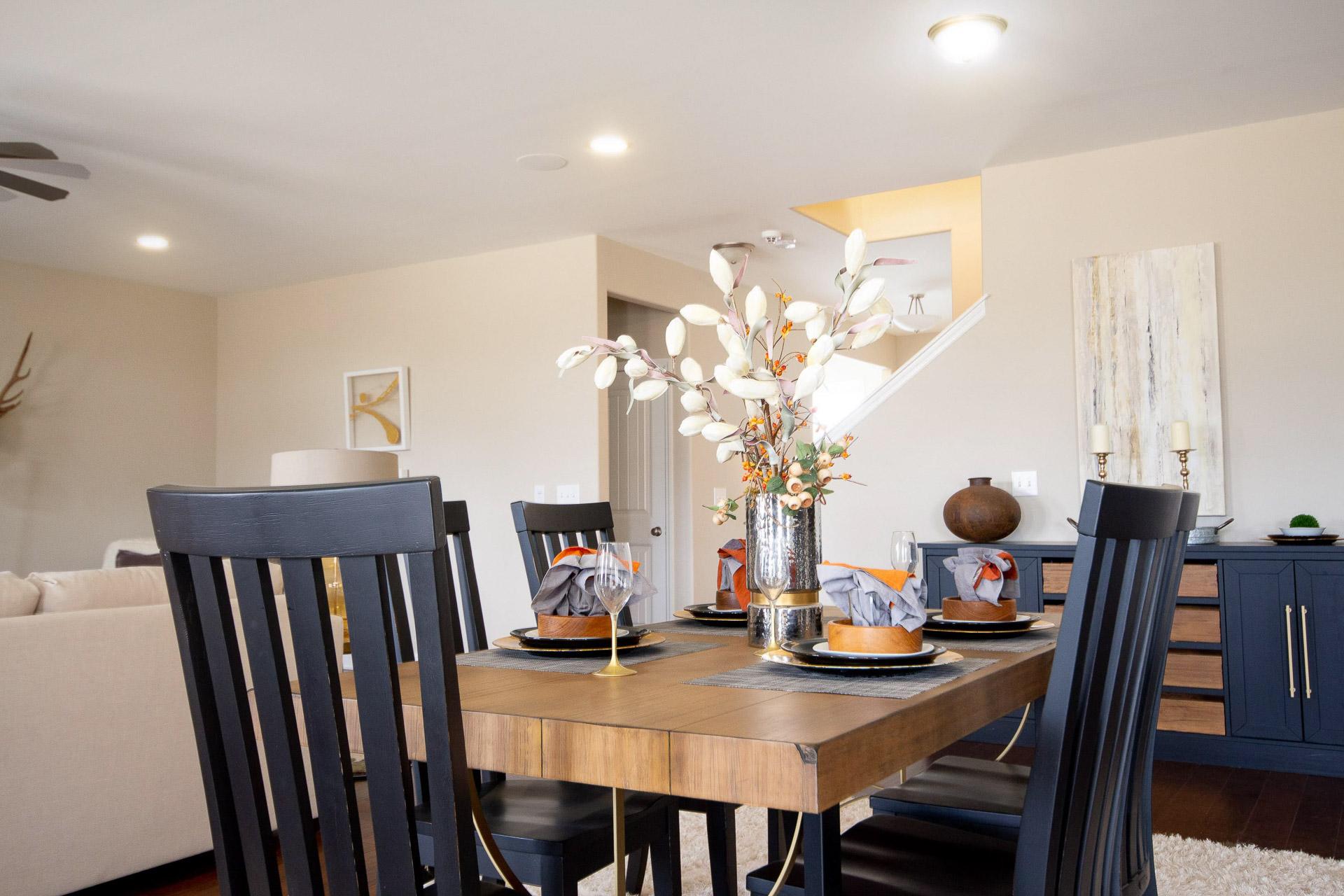 Modern dining room at Summer Pointe in Madison Alabama with wooden table floral centerpiece black chairs and open layout