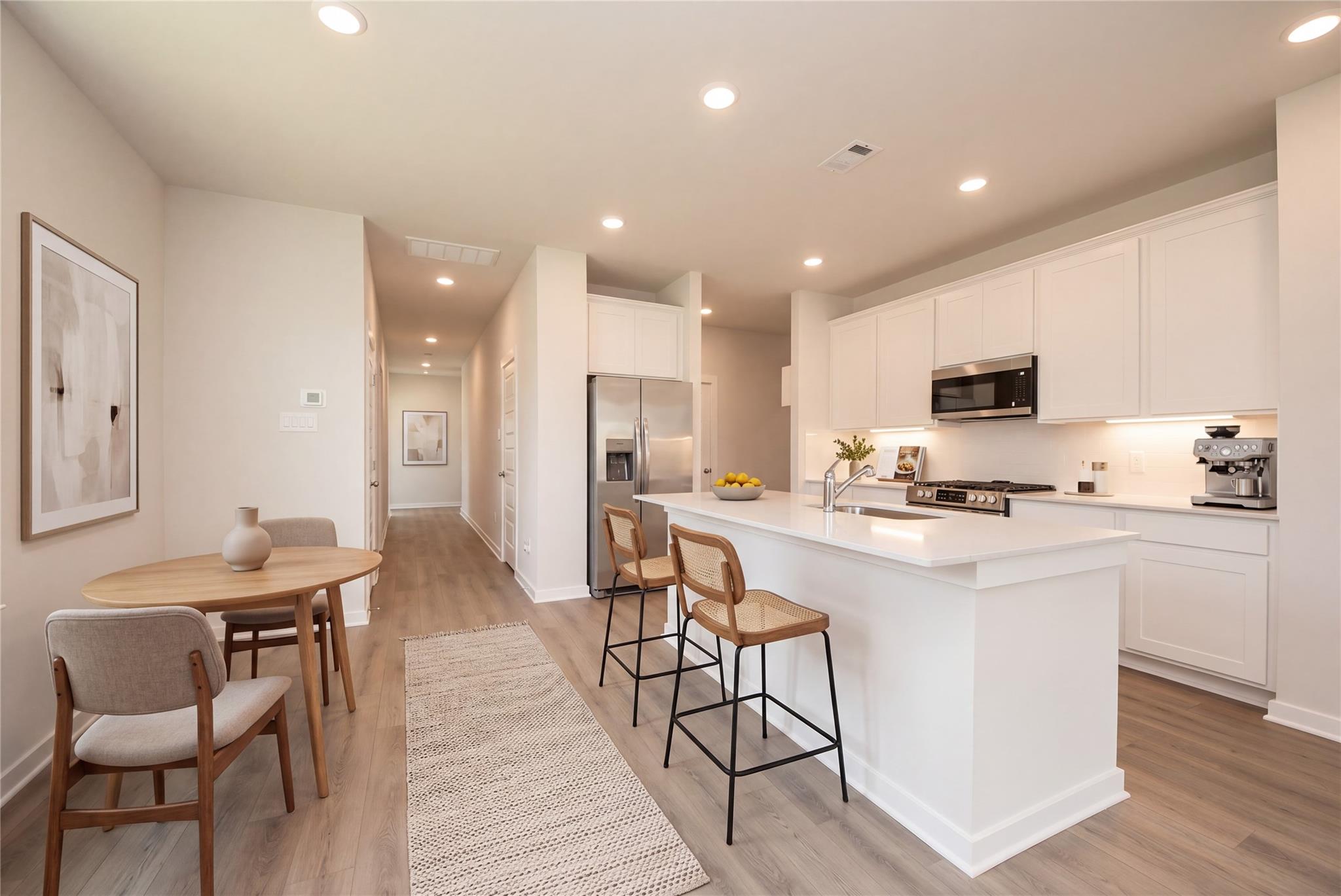Bright open-concept kitchen with white shaker cabinets, island, and breakfast nook in Davidson Homes' The Blanco E, Dayton, Texas