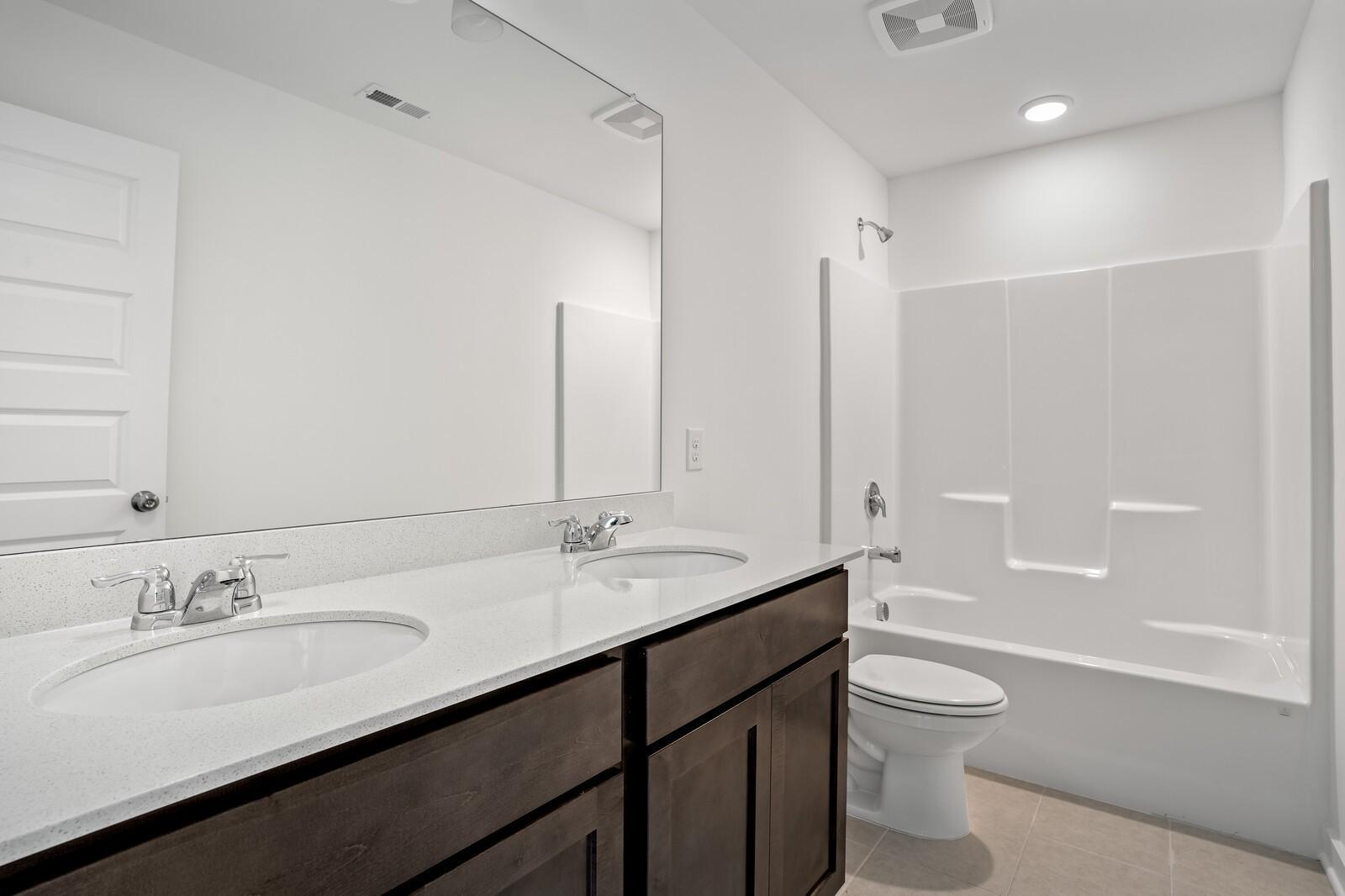Bright guest bathroom featuring double vanity, tub-shower combo, and modern fixtures in Davidson Homes The Logan C, White House, TN