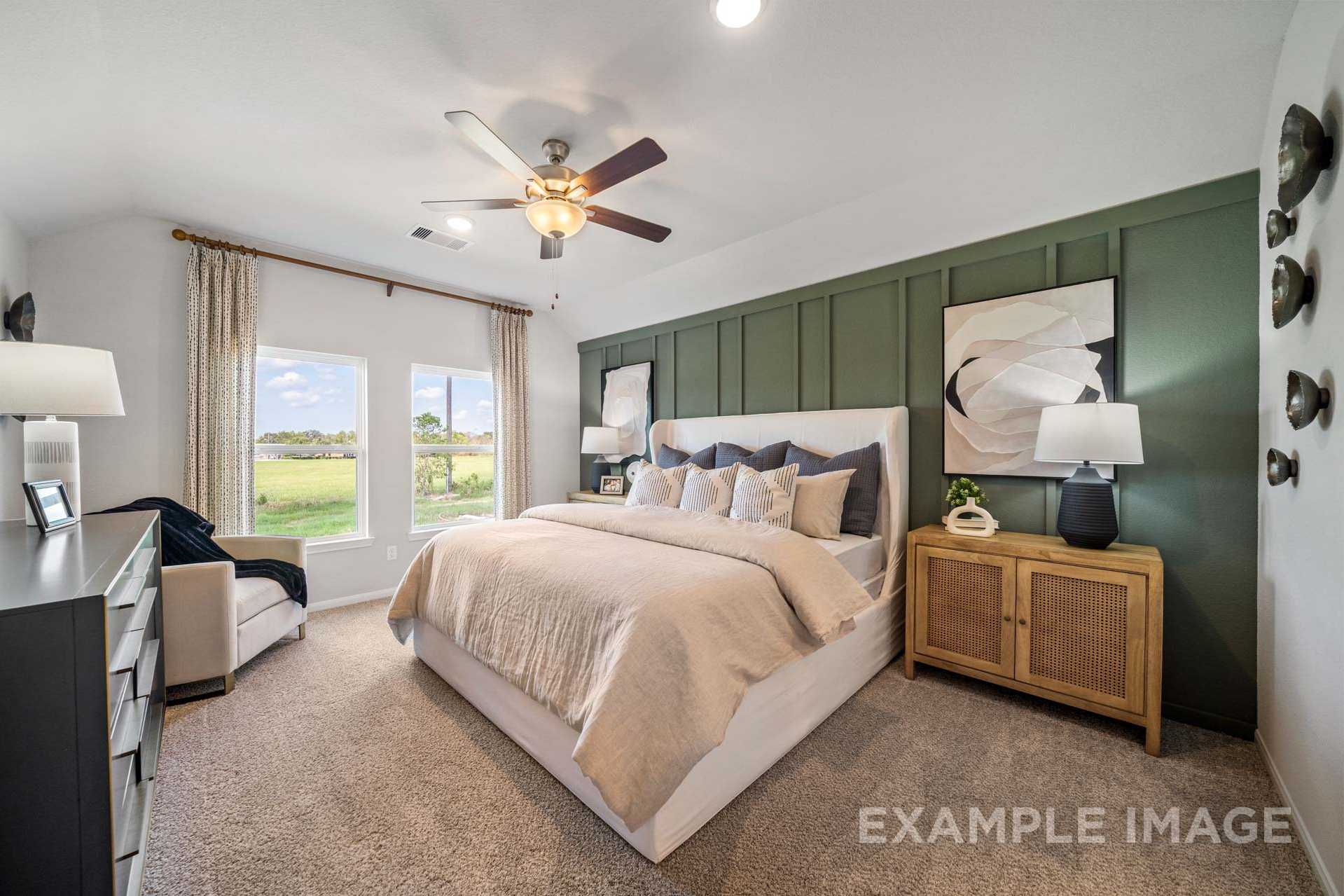 Spacious master bedroom in The Acadia B with king bed, green accent wall, large windows overlooking fields, and modern decor