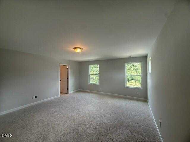 Spacious upstairs bedroom with light gray walls, carpet flooring, and large windows in Davidson Homes The Preston C, Lillington, NC