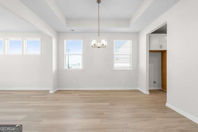 Bright dining room with tray ceiling, chandelier, large windows, and hardwood floors in Davidson Homes The Glenwood C, Hoschton, GA
