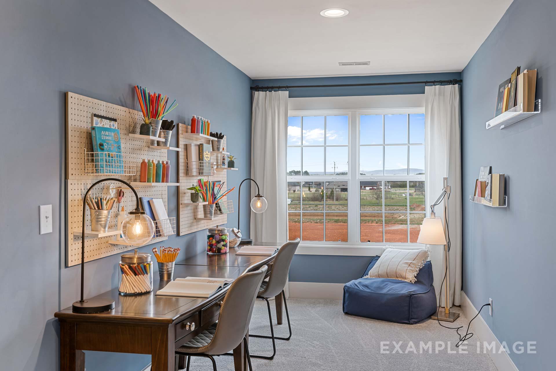 Cozy study nook in The Rockford home design with blue walls, organized desk, built-in shelves, and large window view