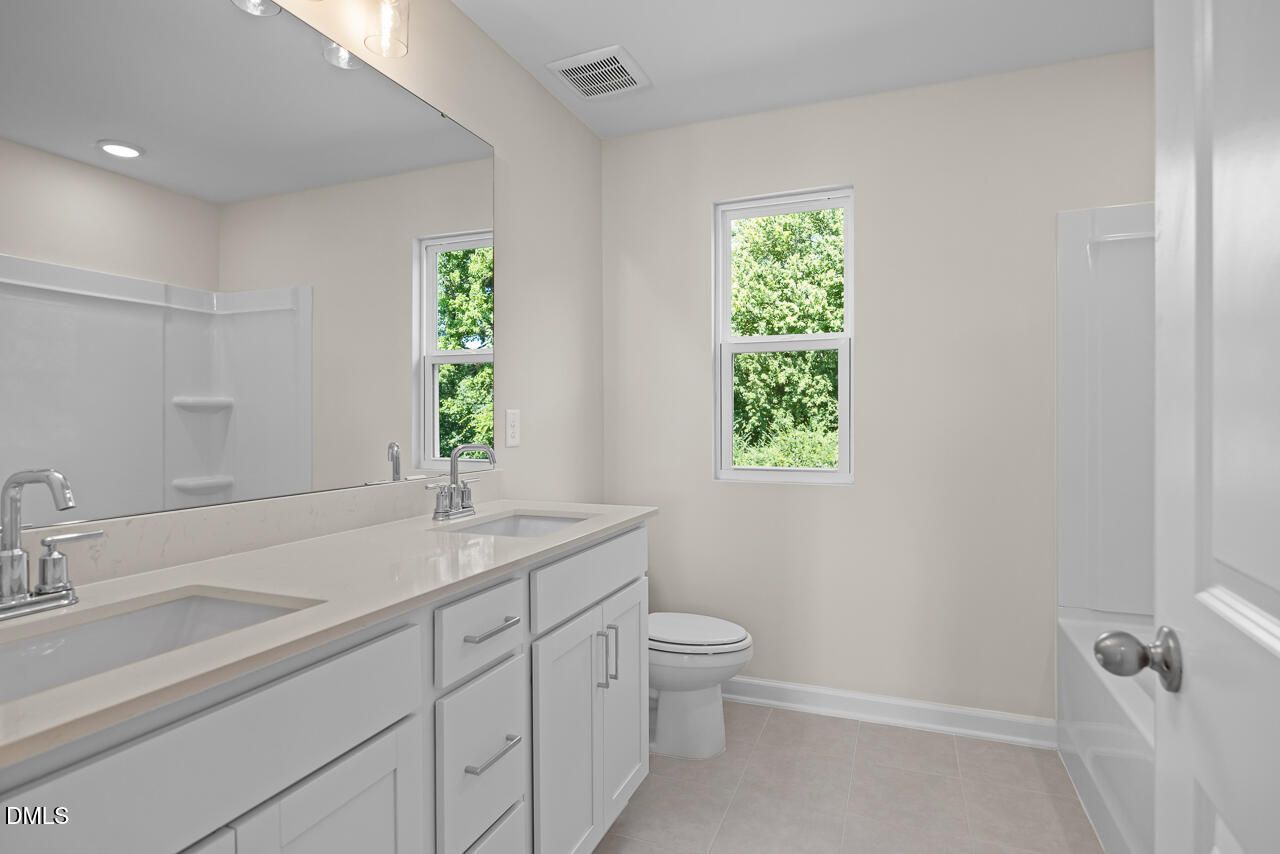Bright white bathroom with double vanity, tub, and garden windows in Davidson Homes The Willow C, Woodland Crossing, Zebulon NC