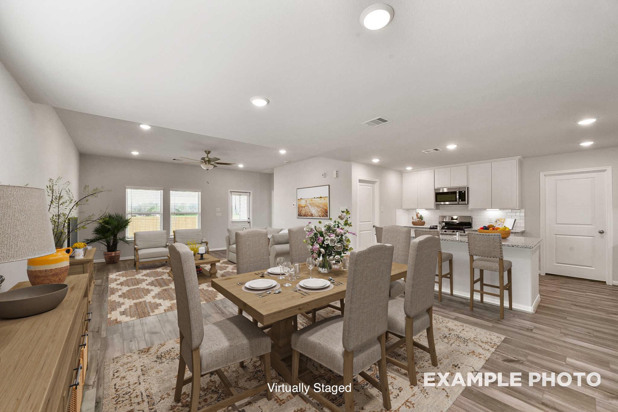 Open-concept dining room with wooden table, upholstered chairs, and rug flowing into white kitchen island in Davidson Homes The Tierra B, Beasley, Texas