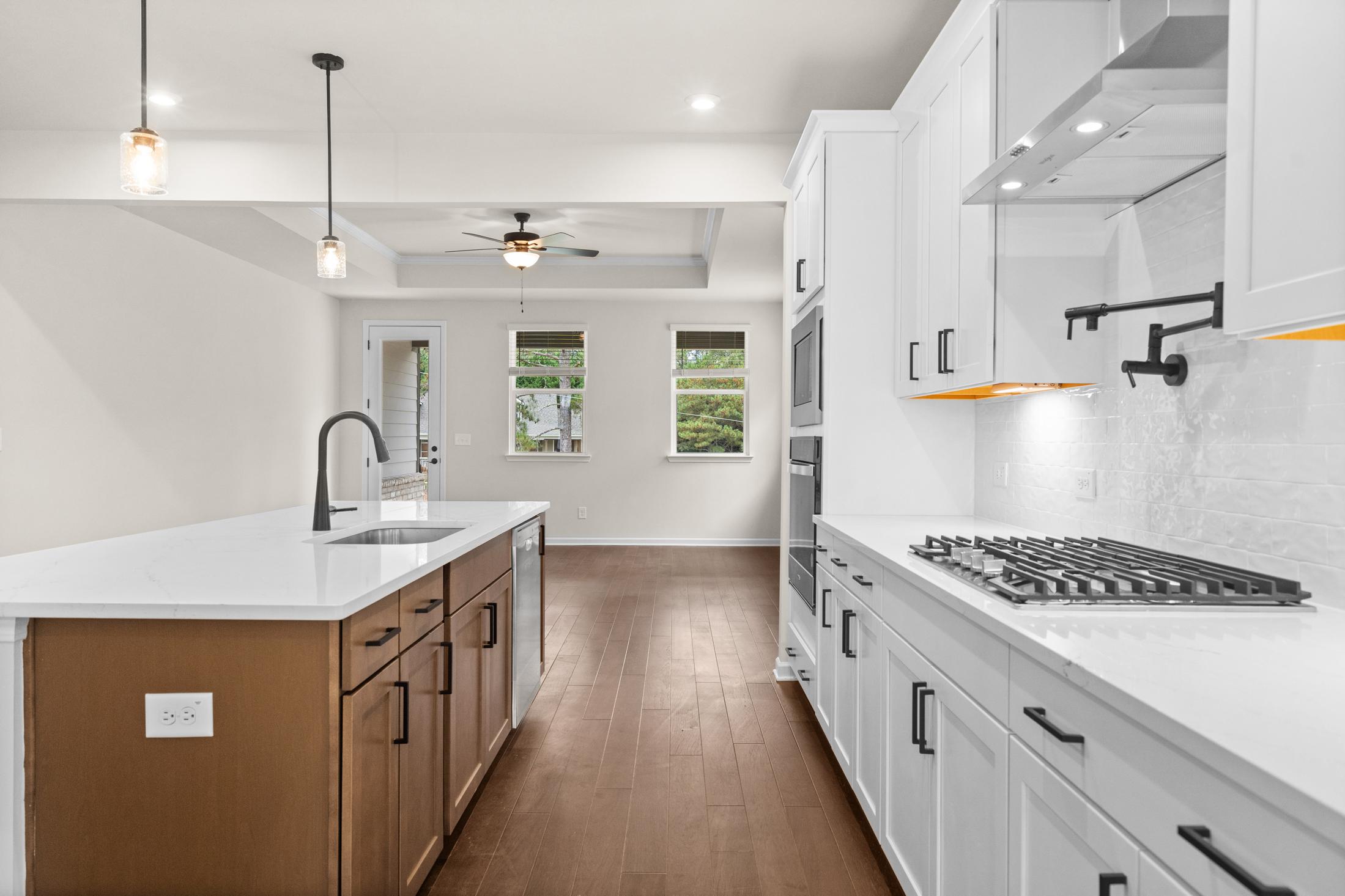 Spacious modern kitchen in The Glenwood with white shaker cabinets, quartz island, gas range, and open layout