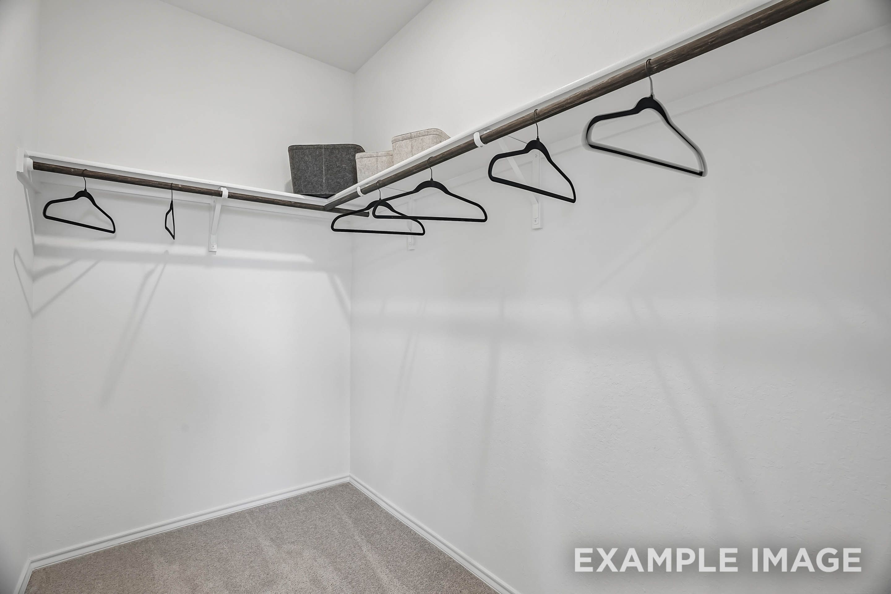 Spacious walk-in closet in The Pinecrest D master suite featuring wall-to-wall shelving and hanging rods.