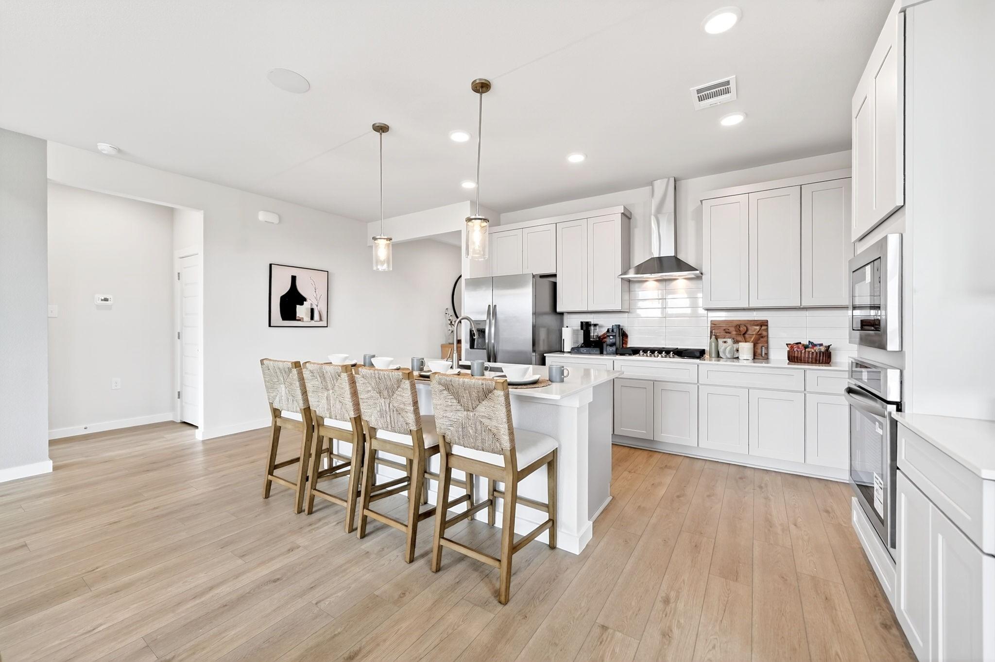 Modern white kitchen with island seating in The Laurel M floor plan at Parks at Foster Crossing in Anna, Texas.