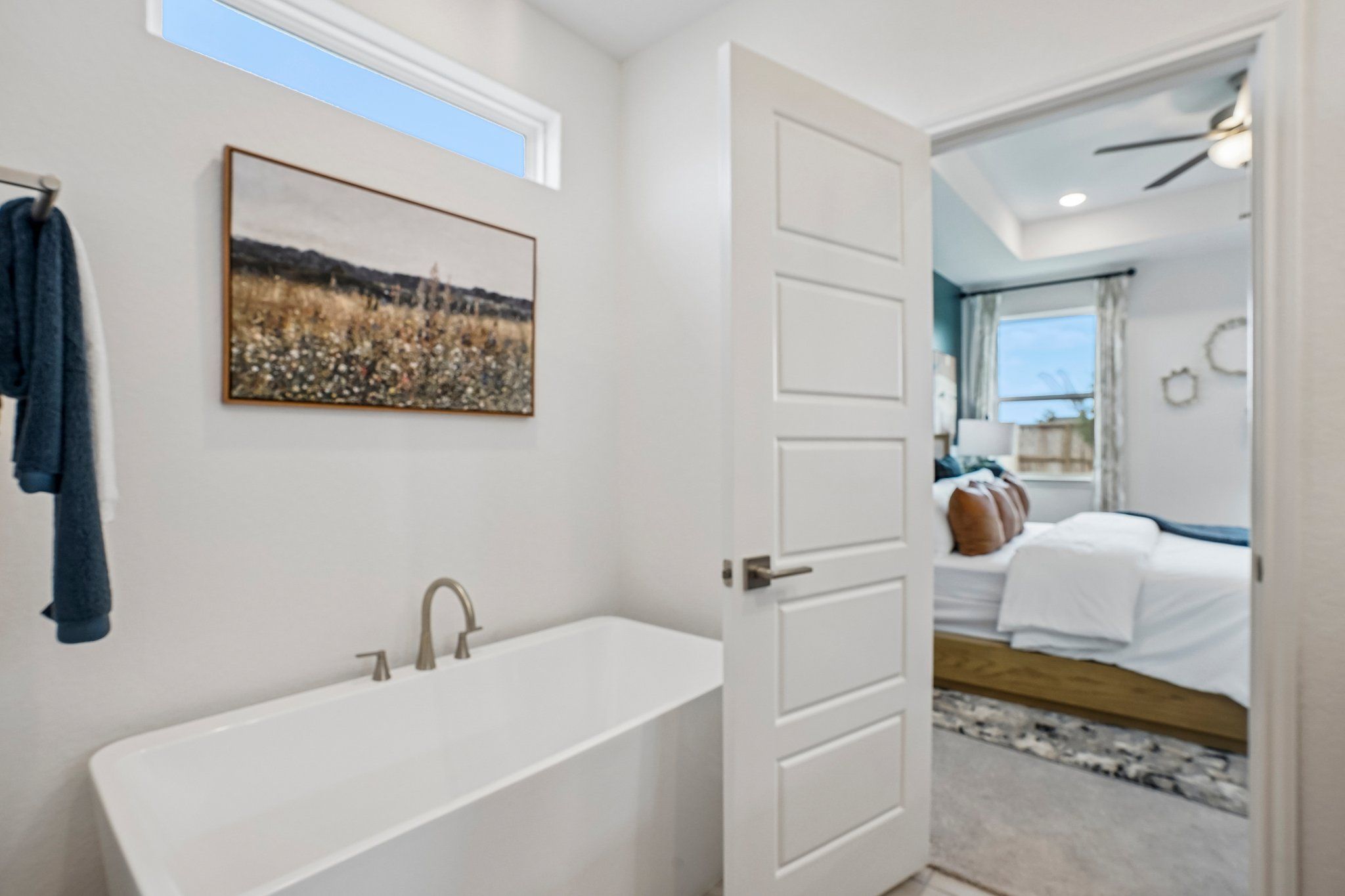 Modern soaking tub in a primary bathroom at Morgan Meadows in San Antonio, Texas, with a view into the bedroom.