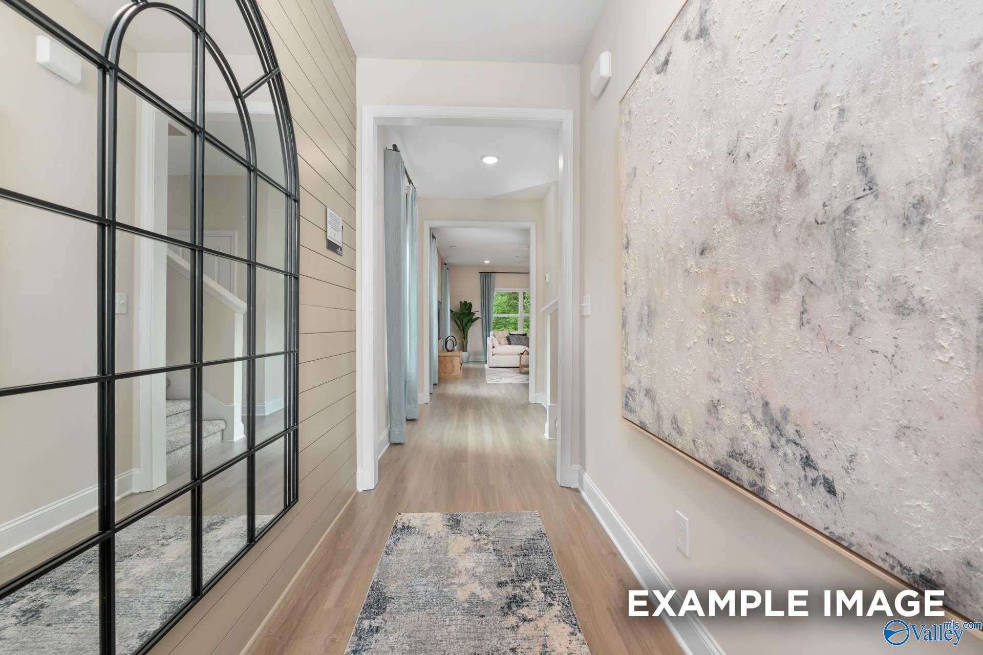 Elegant foyer with arched black mirror, shiplap walls, hardwood floors and abstract art in Davidson Homes The Camden B, Huntsville AL