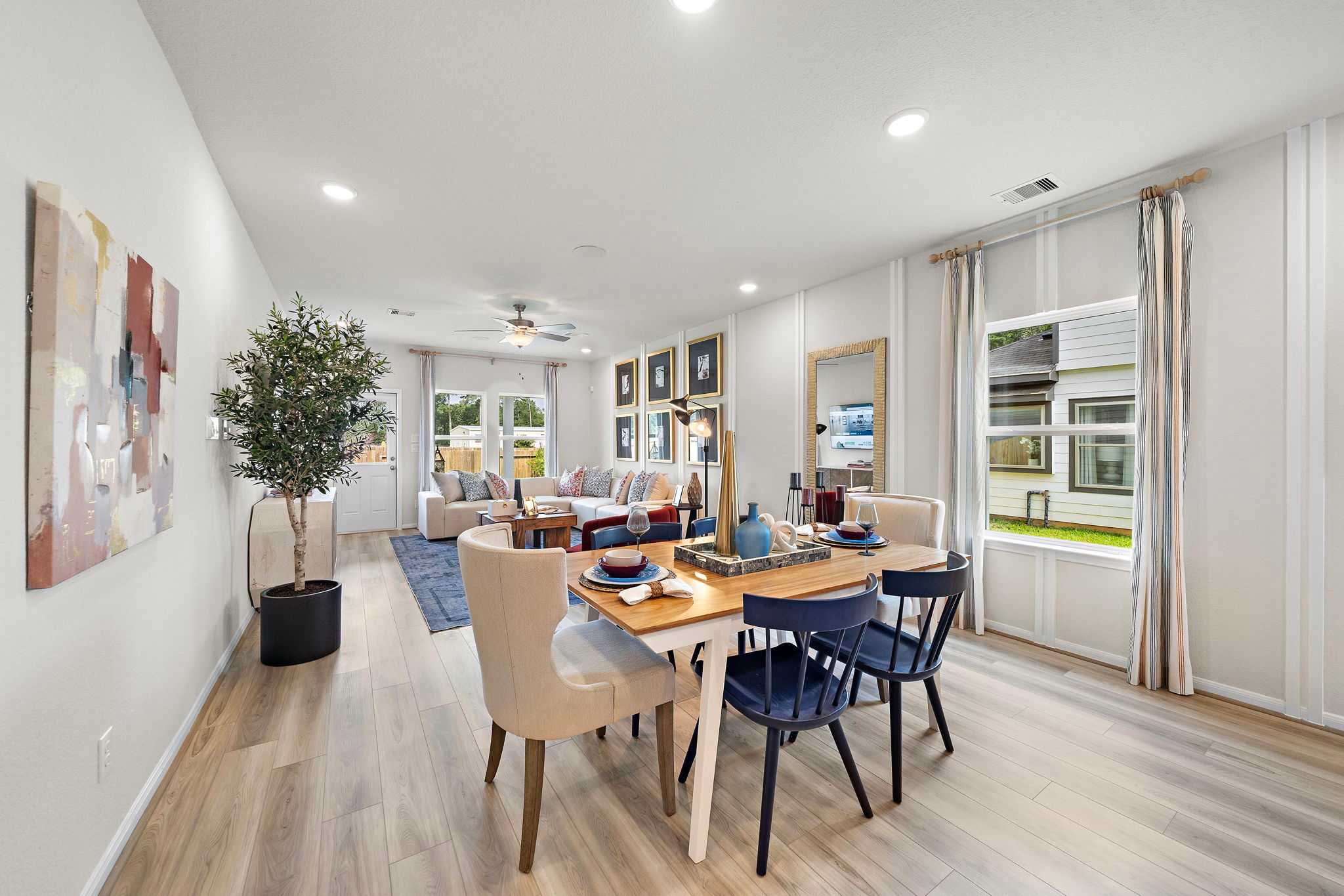 Open-concept living and dining area at Liberty Estates in Cleveland, Texas by Davidson Homes featuring hardwood floors, large windows, and contemporary decor