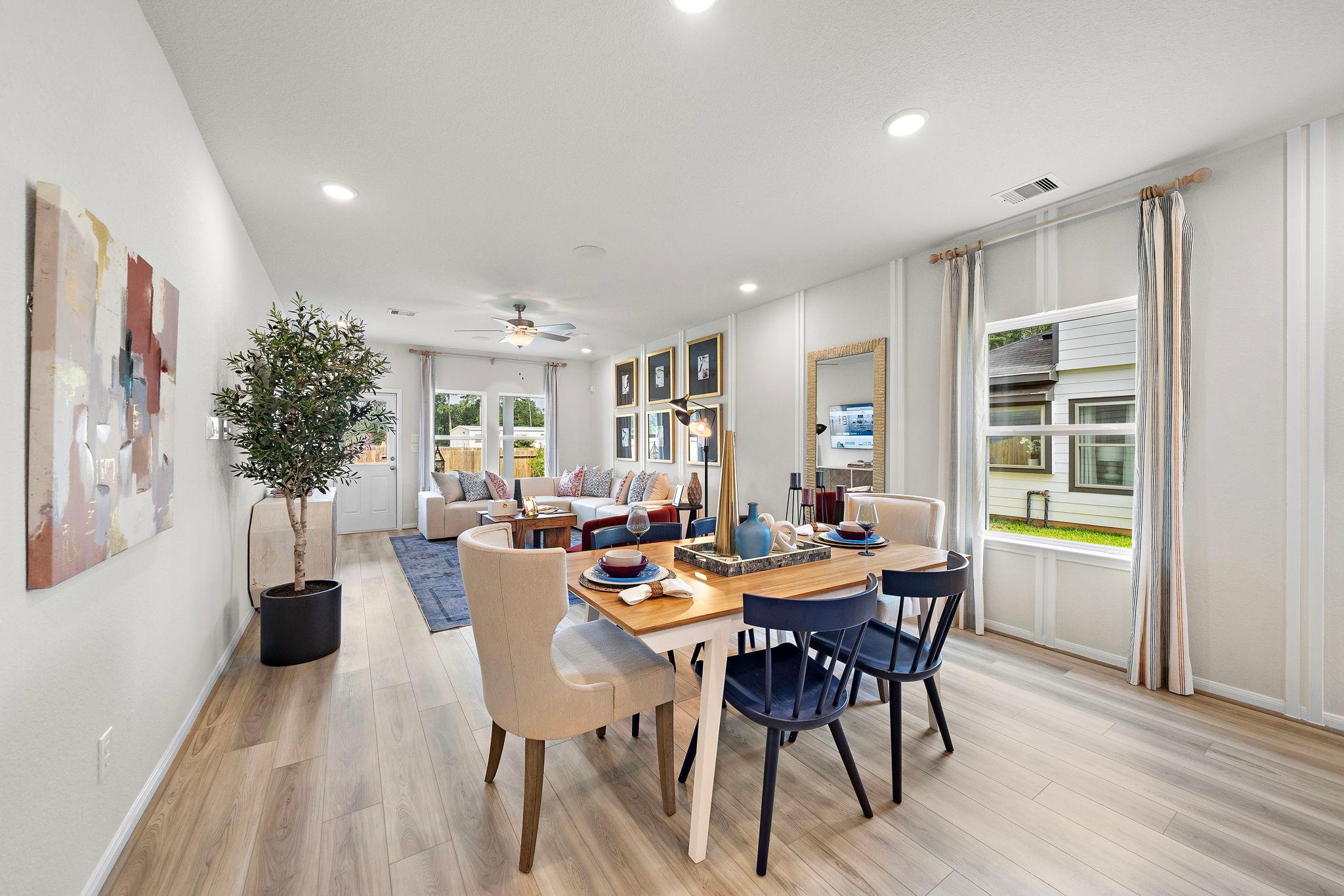 Open-concept living and dining area at Liberty Estates in Cleveland, Texas by Davidson Homes featuring hardwood floors, large windows, and contemporary decor
