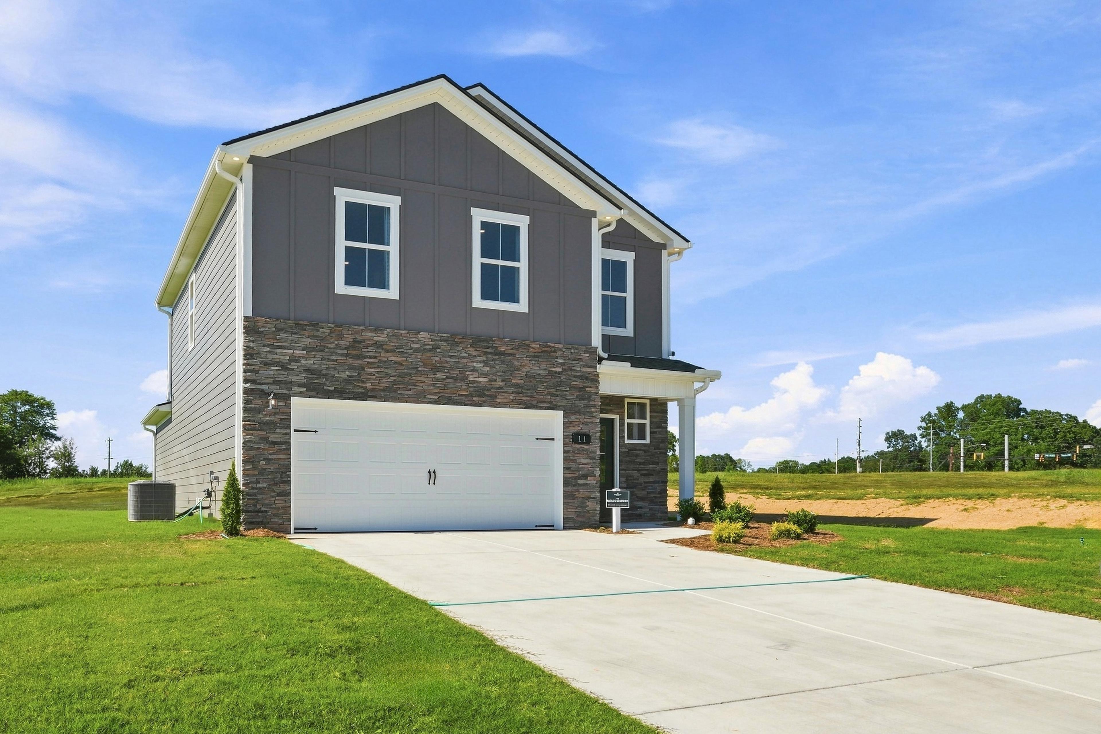 Two-story gray and stone new construction home with two-car garage at Bailey Park by Davidson Homes in Fayetteville, Tennessee