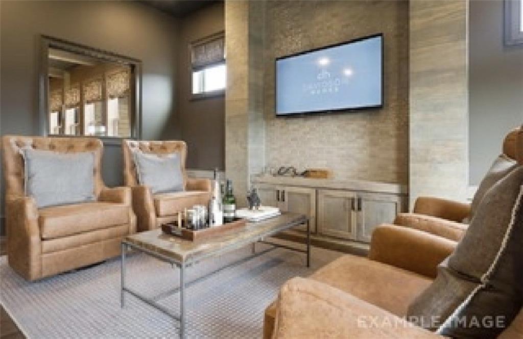 Cozy media room with leather armchairs, mounted TV on stone accent wall in Davidson Homes Seaside A, Woodstock, GA