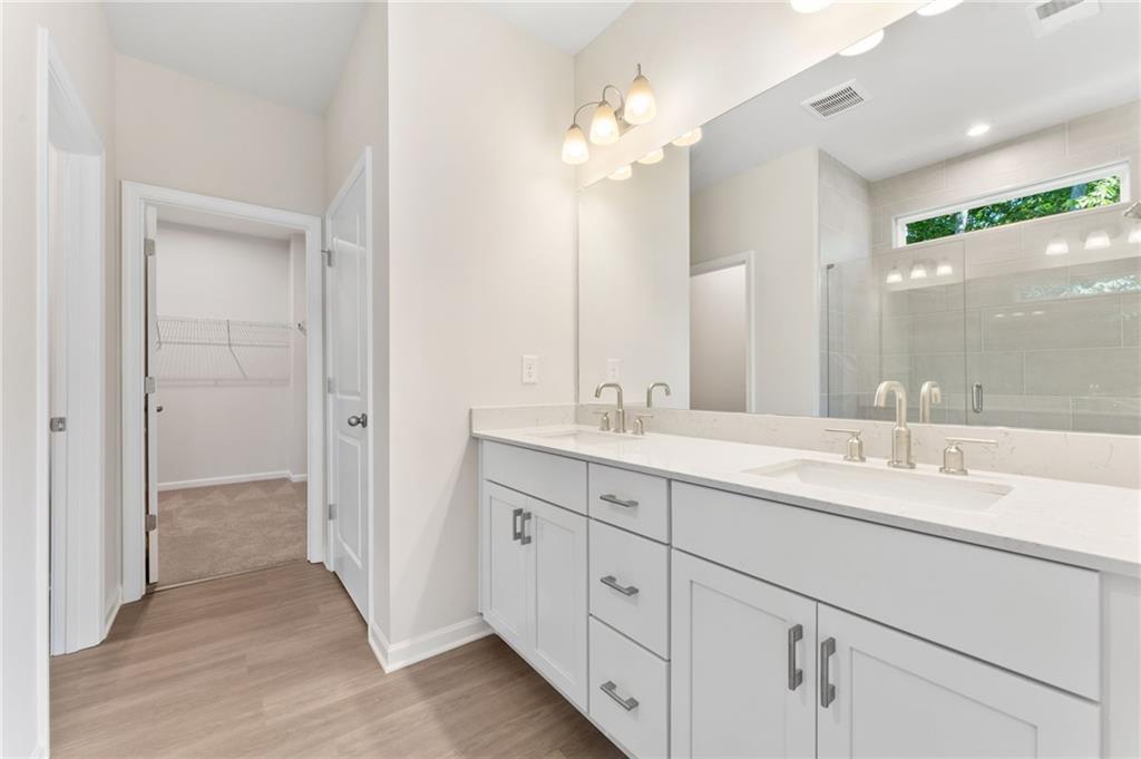 Elegant master bathroom with double white vanity, glass shower enclosure, and linen closet in Davidson Homes The Ash B plan, Riverwood, Dallas, Georgia