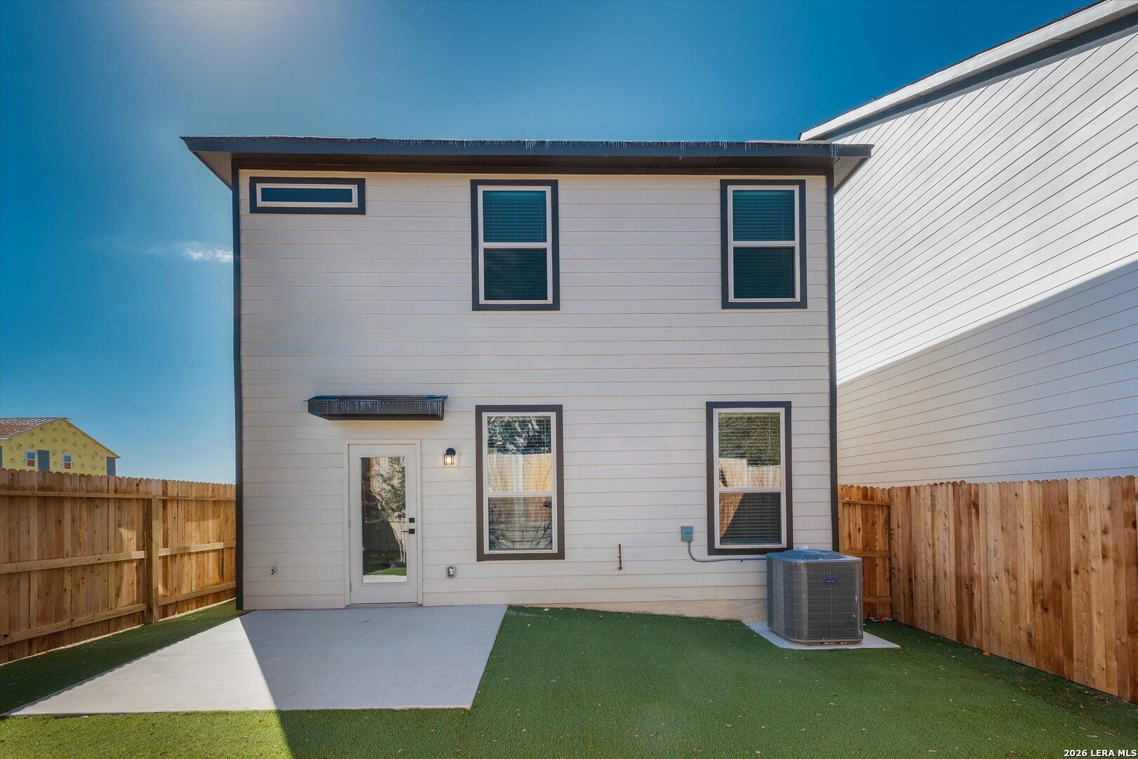 Two-story Charlotte A home rear exterior with covered patio, concrete slab, fenced grassy backyard in San Antonio, Texas