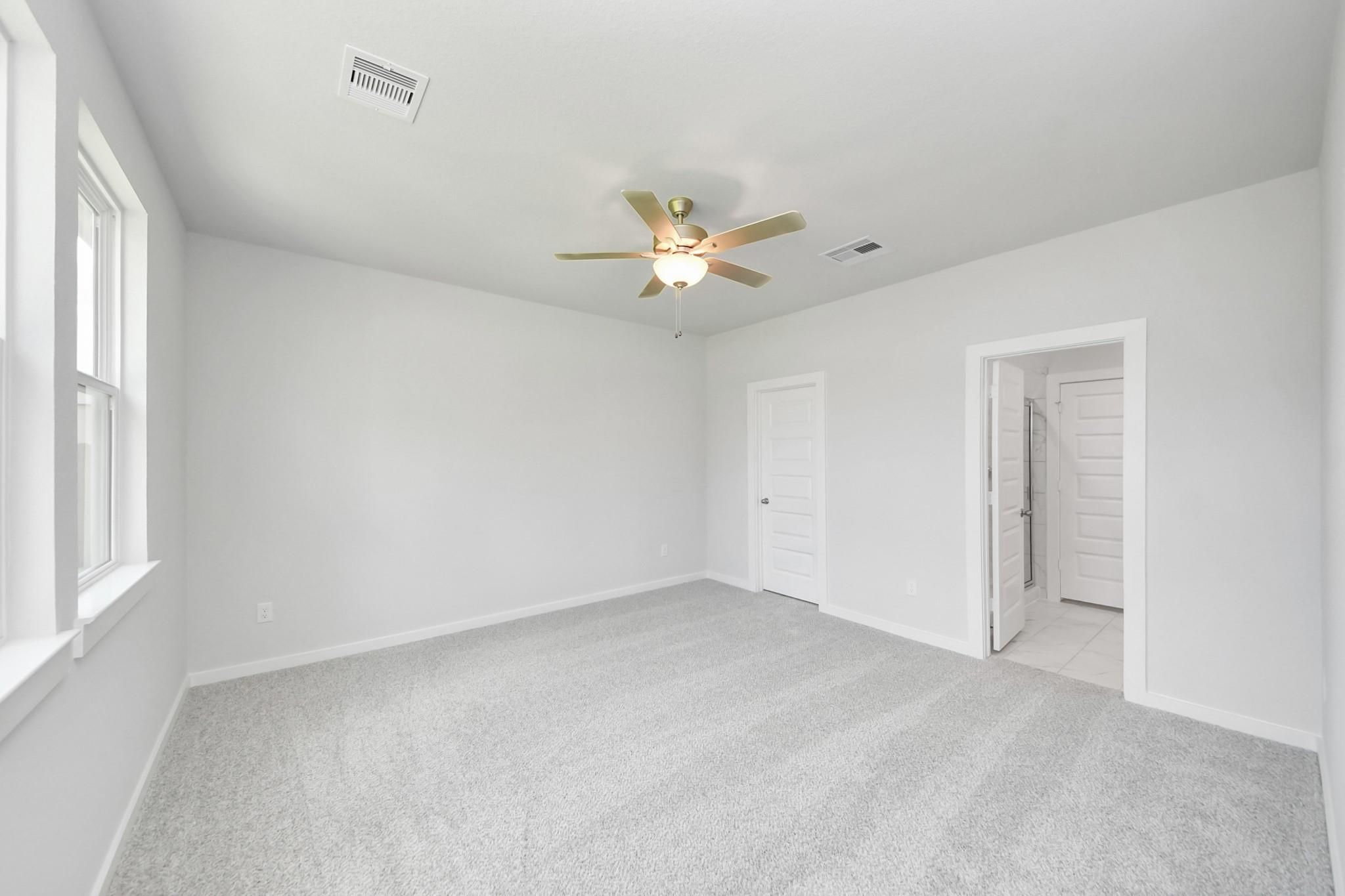 Bright bedroom with neutral carpet and ceiling fan in The Sabine F floor plan at Liberty Estates, Cleveland, Texas.