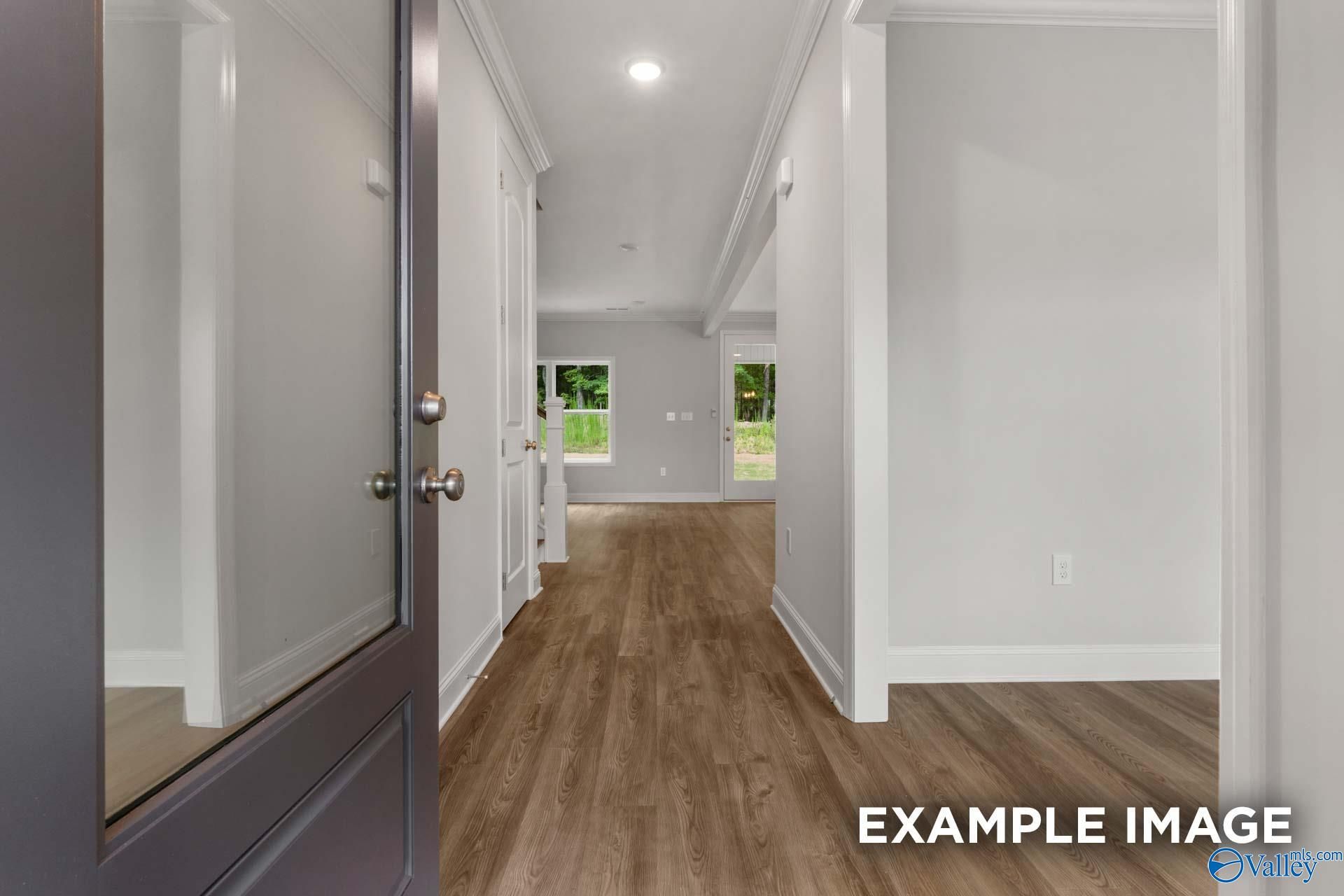 Bright entry hallway with luxury vinyl plank floors, white walls, and backyard view in Davidson Homes The Shelby C, Arab AL