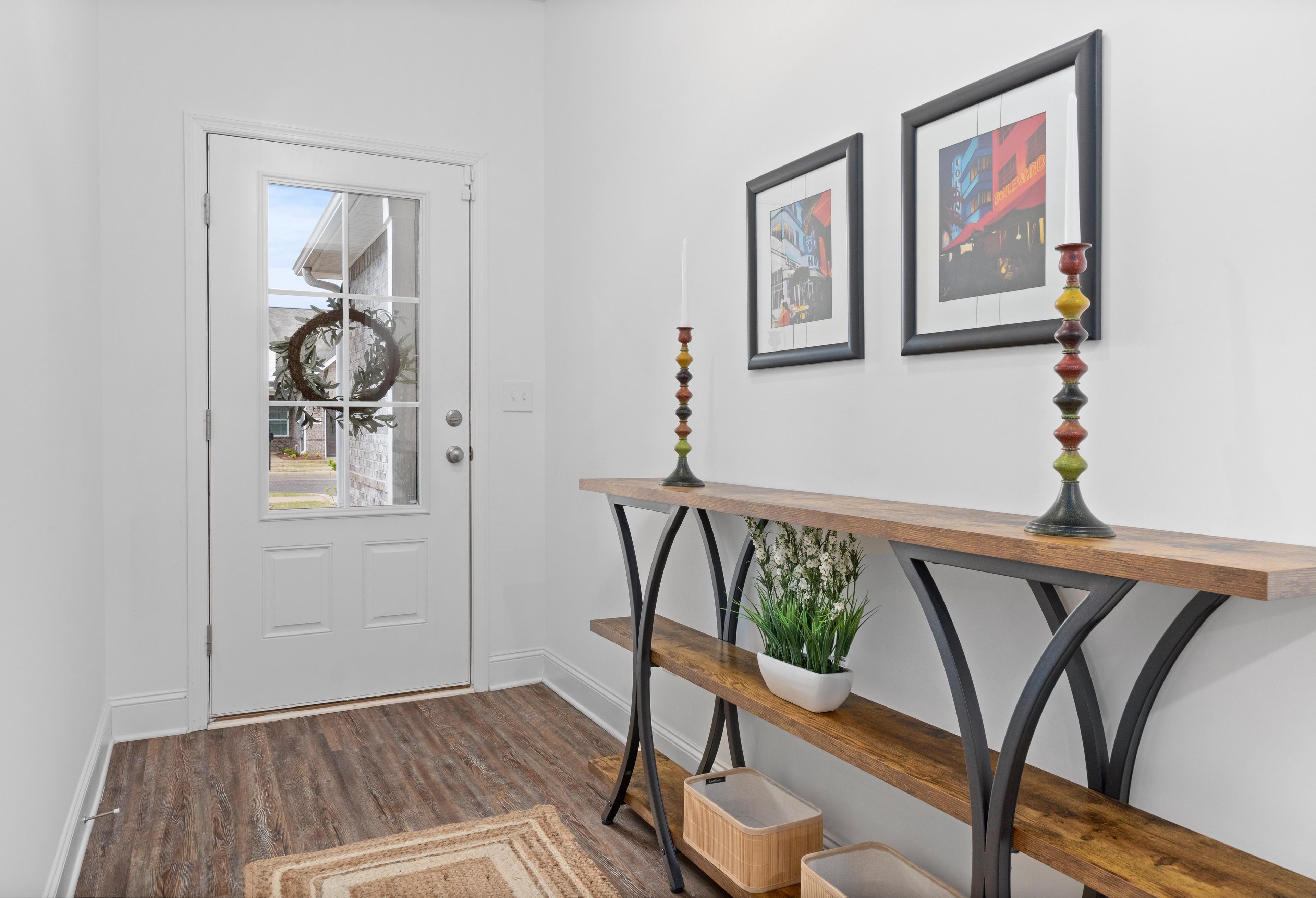 Welcoming entryway in The Cumberland Davidson Homes design with glass-paneled door, holiday wreath, wooden console table, potted plant, and abstract art