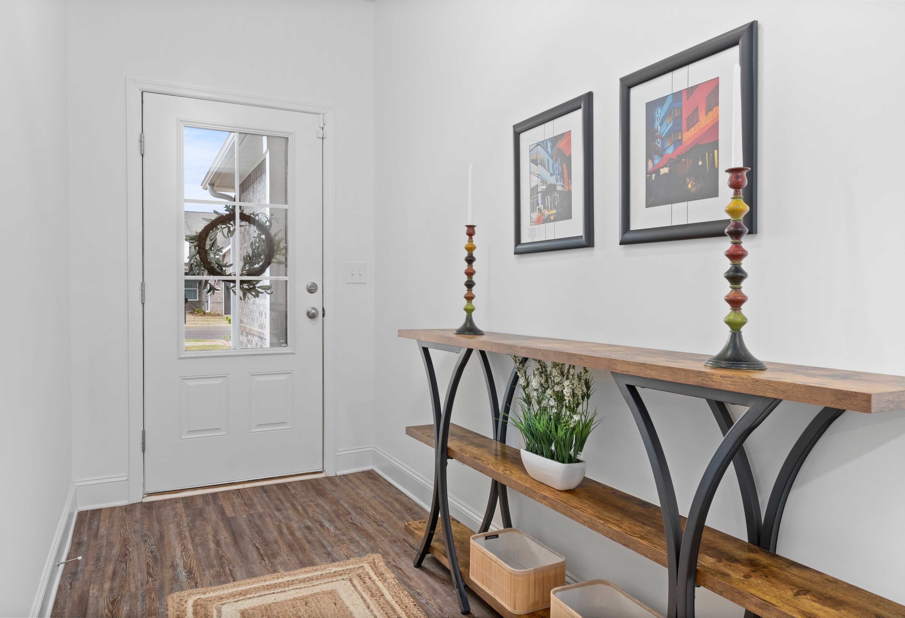 Welcoming entryway in The Cumberland Davidson Homes design with glass-paneled door, holiday wreath, wooden console table, potted plant, and abstract art