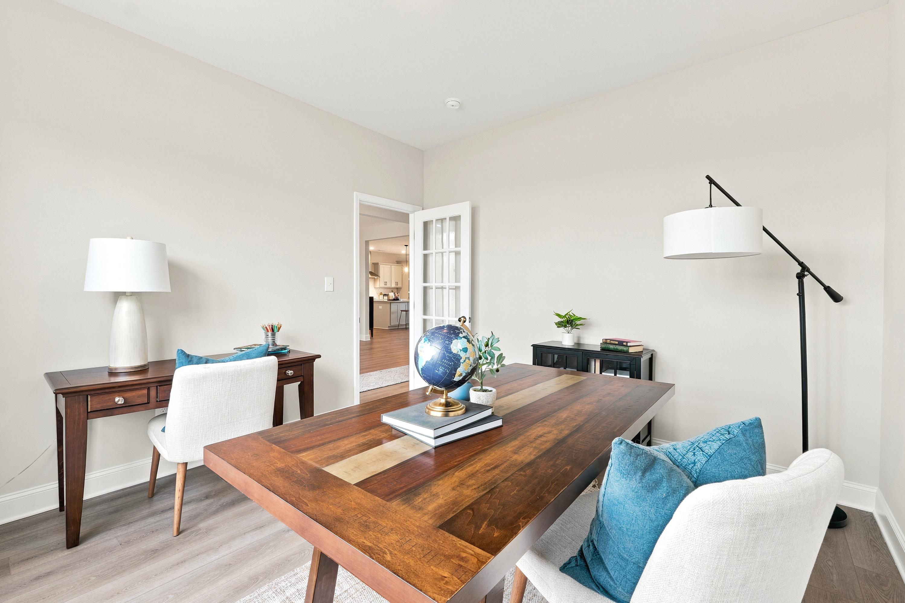 Home office at Riverton Preserve in Huntsville, AL by Davidson Homes featuring a large wooden desk and modern decor.