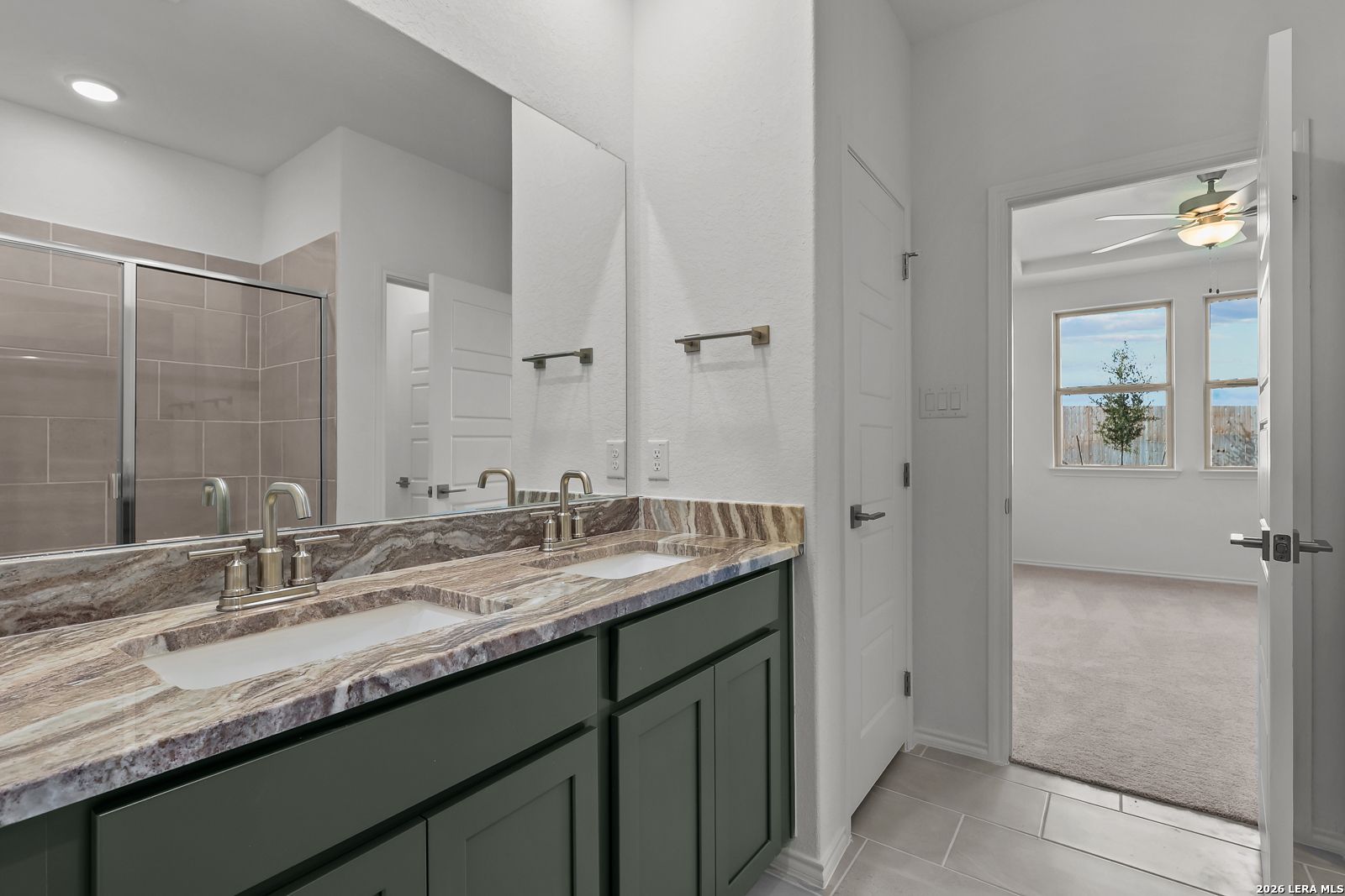 Double vanity with granite countertop and tiled shower in Davidson Homes Brazos B floor plan, Agave, San Antonio, Texas.