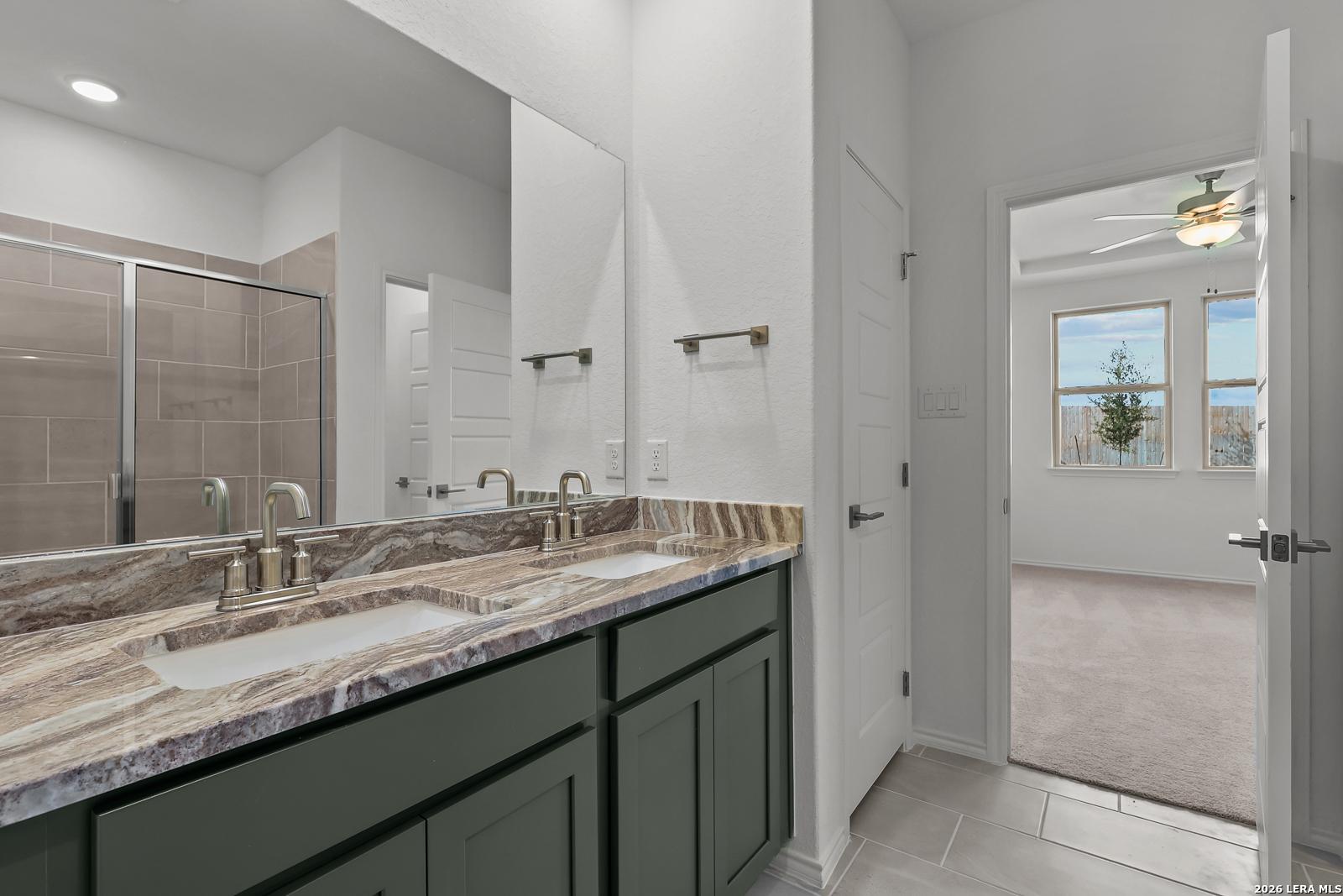 Double vanity with granite countertop and tiled shower in Davidson Homes Brazos B floor plan, Agave, San Antonio, Texas.