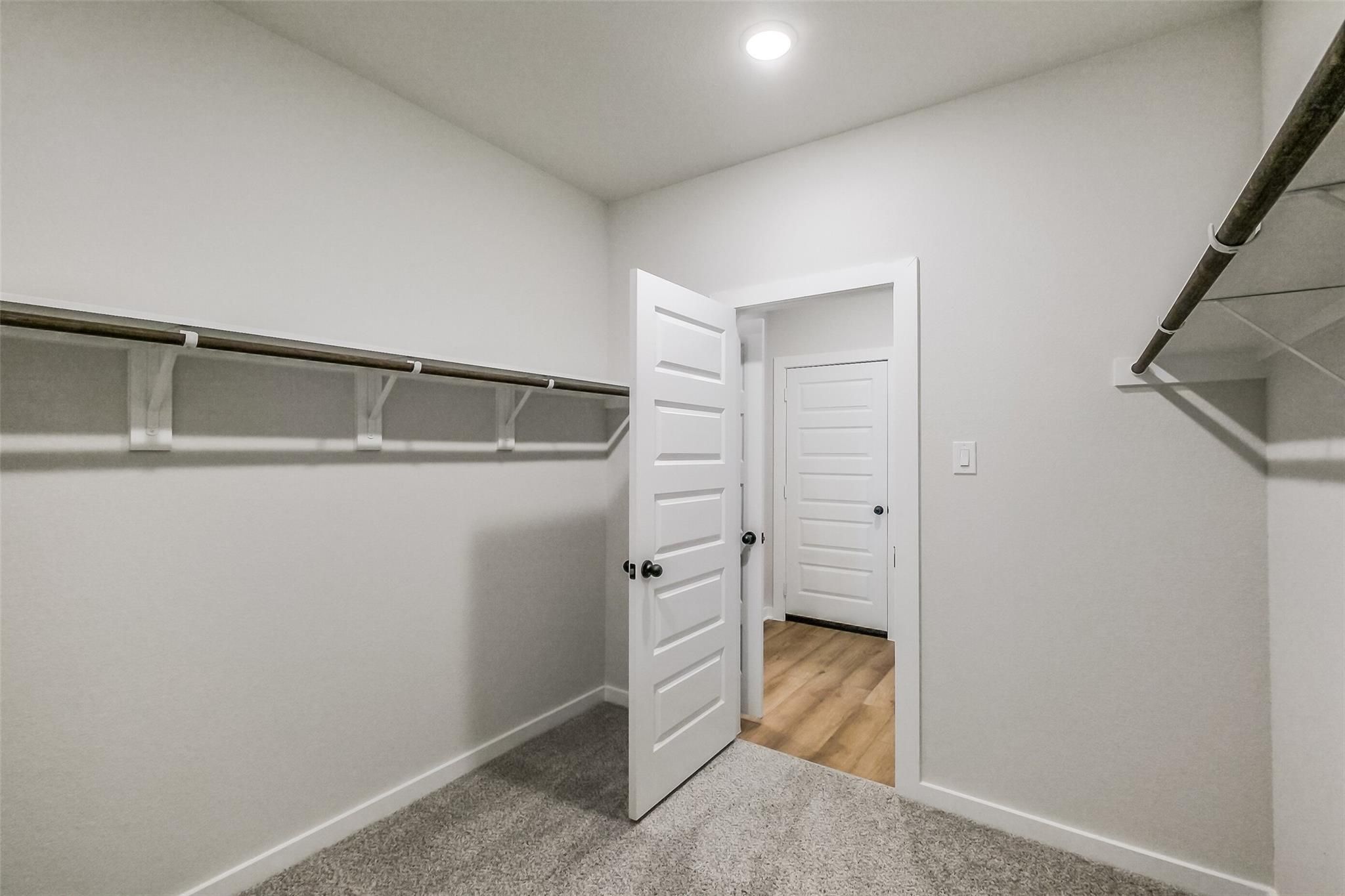 Spacious walk-in closet with built-in shelves and hanging rods in Davidson Homes The Tierra B, Emberly, Beasley, Texas