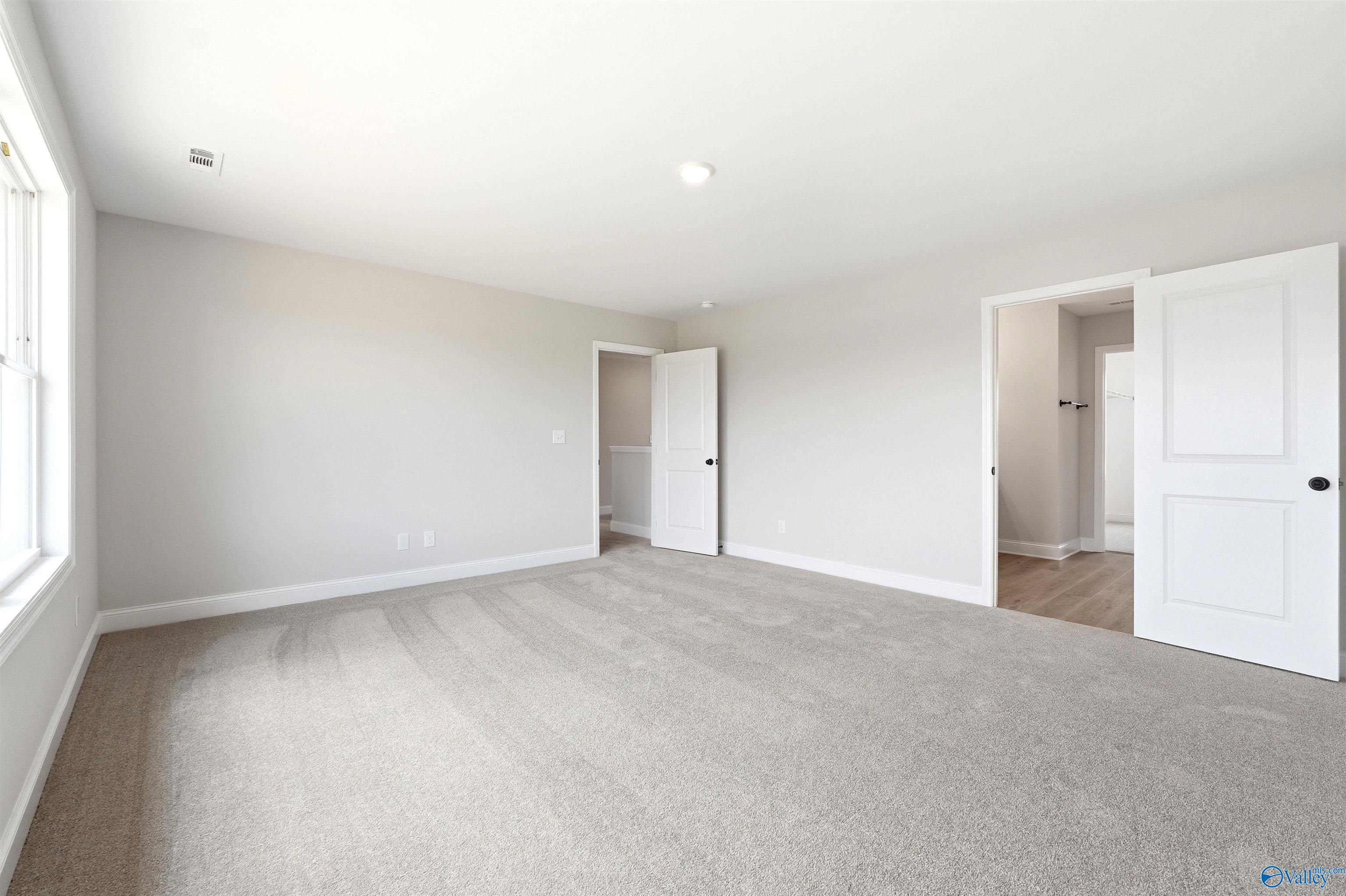 Spacious, carpeted bedroom with neutral walls in The Shelby A floor plan at Wood Trail in Toney, Alabama.