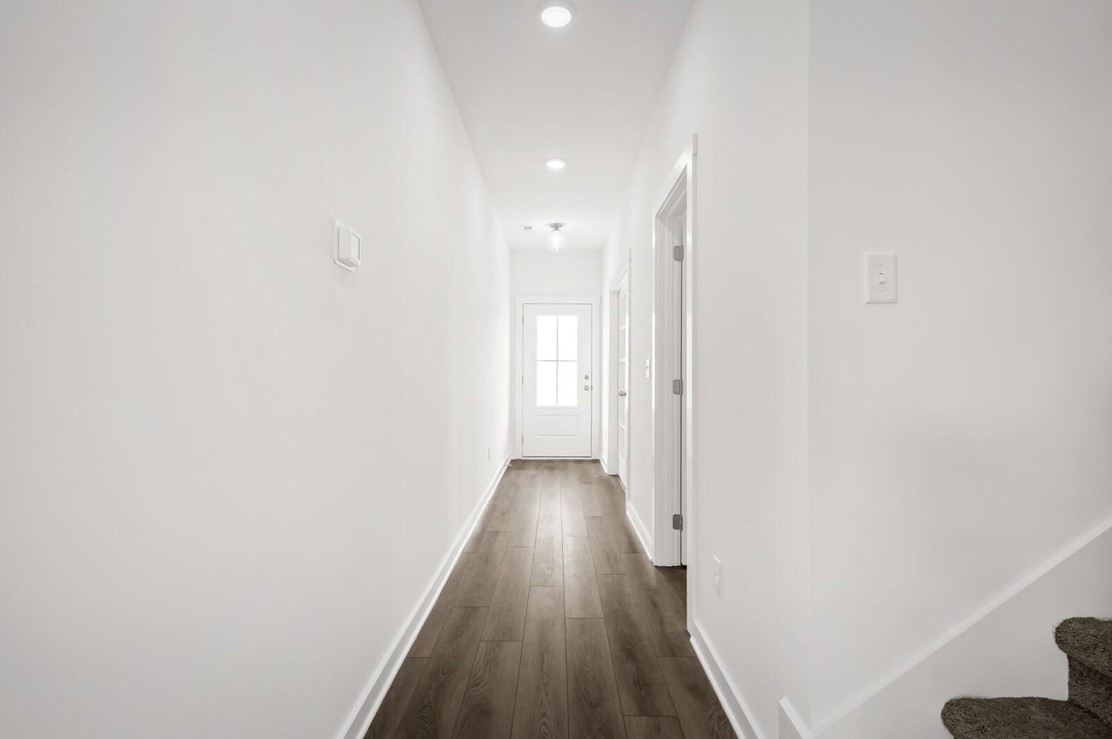 Bright, modern hallway with wood-style flooring in The Logan C floor plan at Calista Farms, White House, Tennessee.
