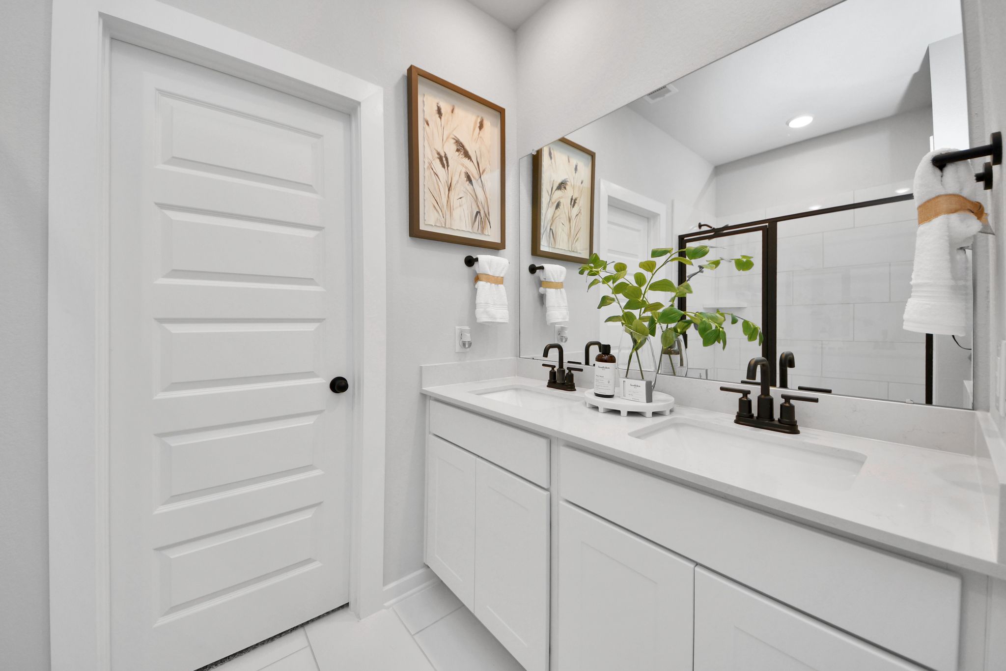 Modern double vanity bathroom at Robins Landing in Houston, TX by Davidson Homes with white cabinets and quartz countertops.