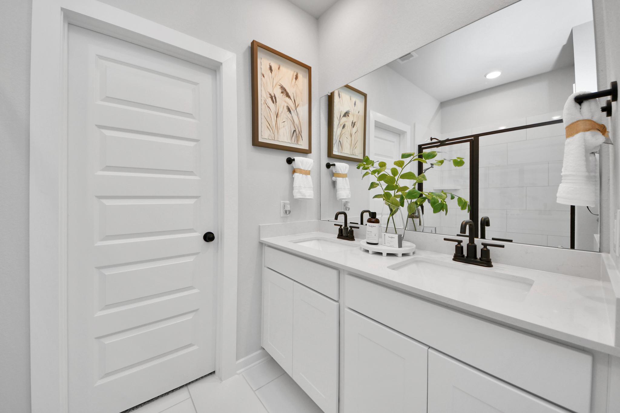 Modern double vanity bathroom at Robins Landing in Houston, TX by Davidson Homes with white cabinets and quartz countertops.
