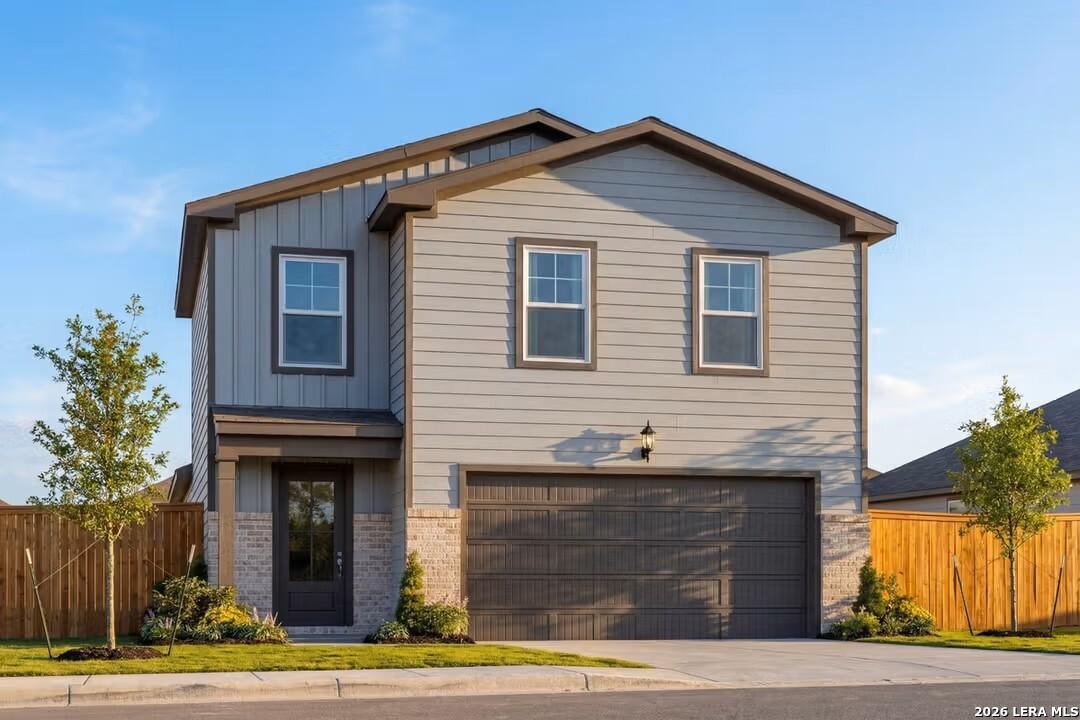 Modern 2-story home with gray siding, brick accents, 2-car garage, and front porch in Applewhite Meadows, San Antonio, Texas