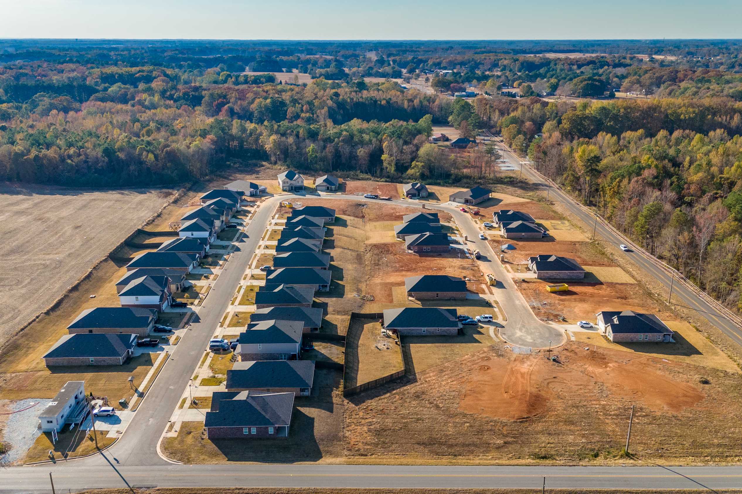 Aerial view of new homes in Mallard Landing Athens Alabama with dark roofs construction sites and surrounding woods fields