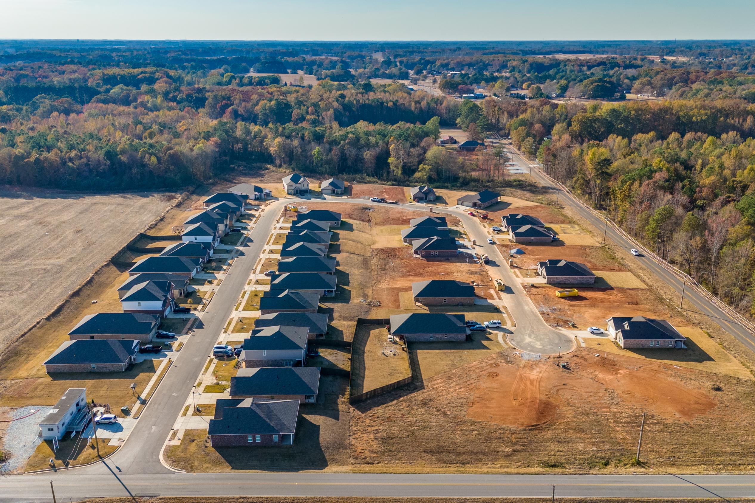 Aerial view of new homes in Mallard Landing Athens Alabama with dark roofs construction sites and surrounding woods fields