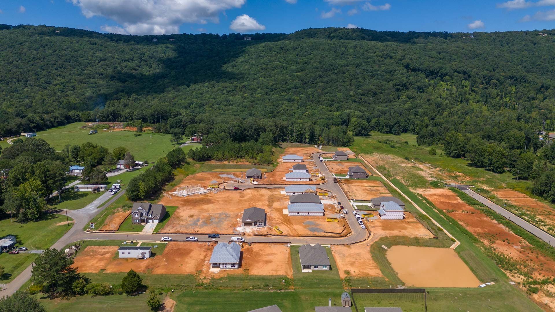 Aerial view of new homes under construction at Watts Glen in Owens Cross Roads Alabama surrounded by green forests and mountains