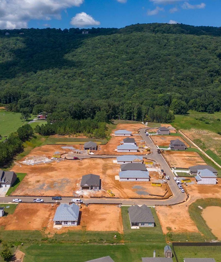 Aerial view of new homes under construction at Watts Glen in Owens Cross Roads Alabama surrounded by green forests and mountains