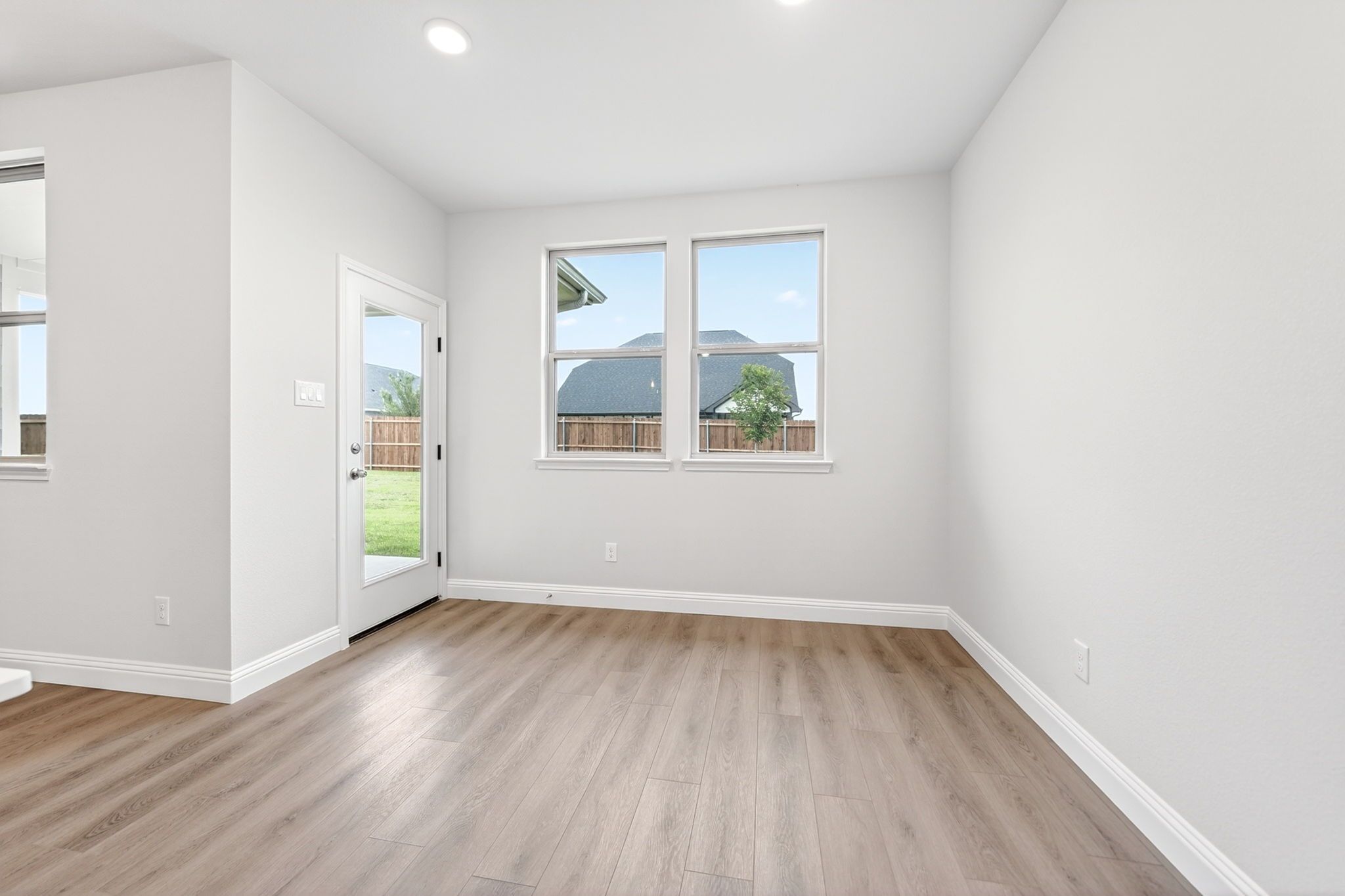 Bright breakfast nook in The Redbud by Davidson Homes featuring wood-look flooring and backyard access.