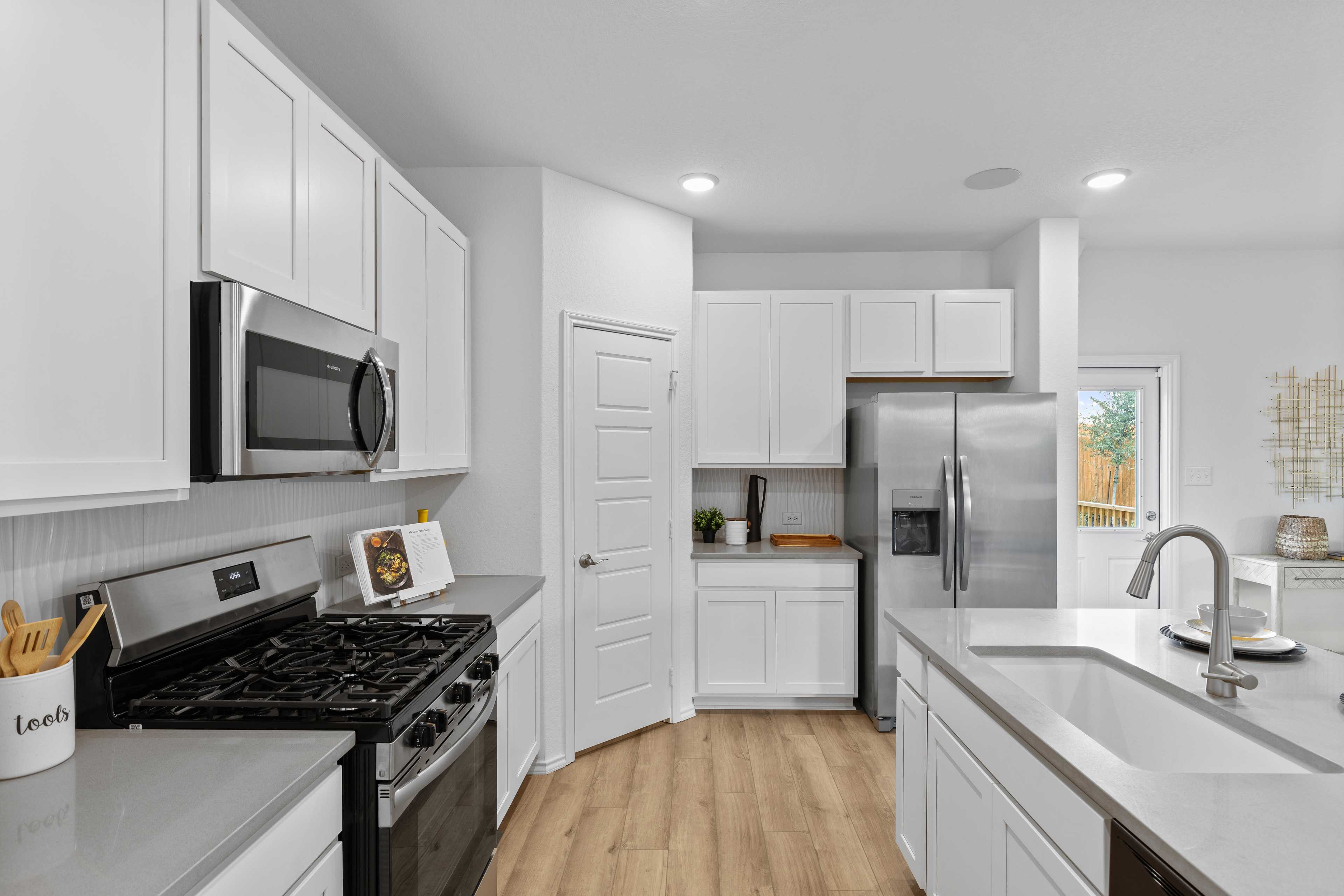 Spacious modern kitchen at Horizon Pointe in Converse, Texas with white shaker cabinets, stainless steel appliances, and hardwood floors
