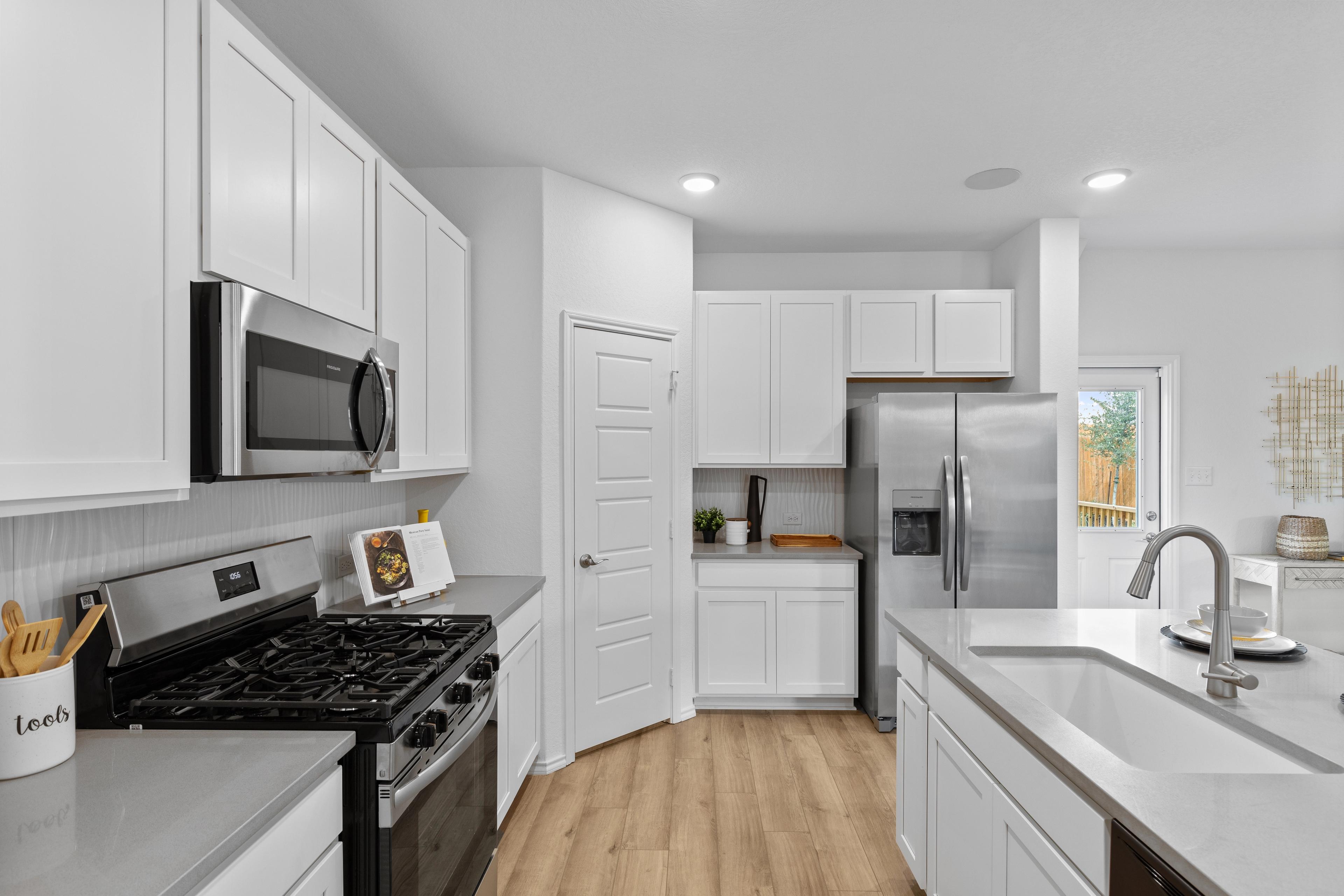 Spacious modern kitchen at Horizon Pointe in Converse, Texas with white shaker cabinets, stainless steel appliances, and hardwood floors
