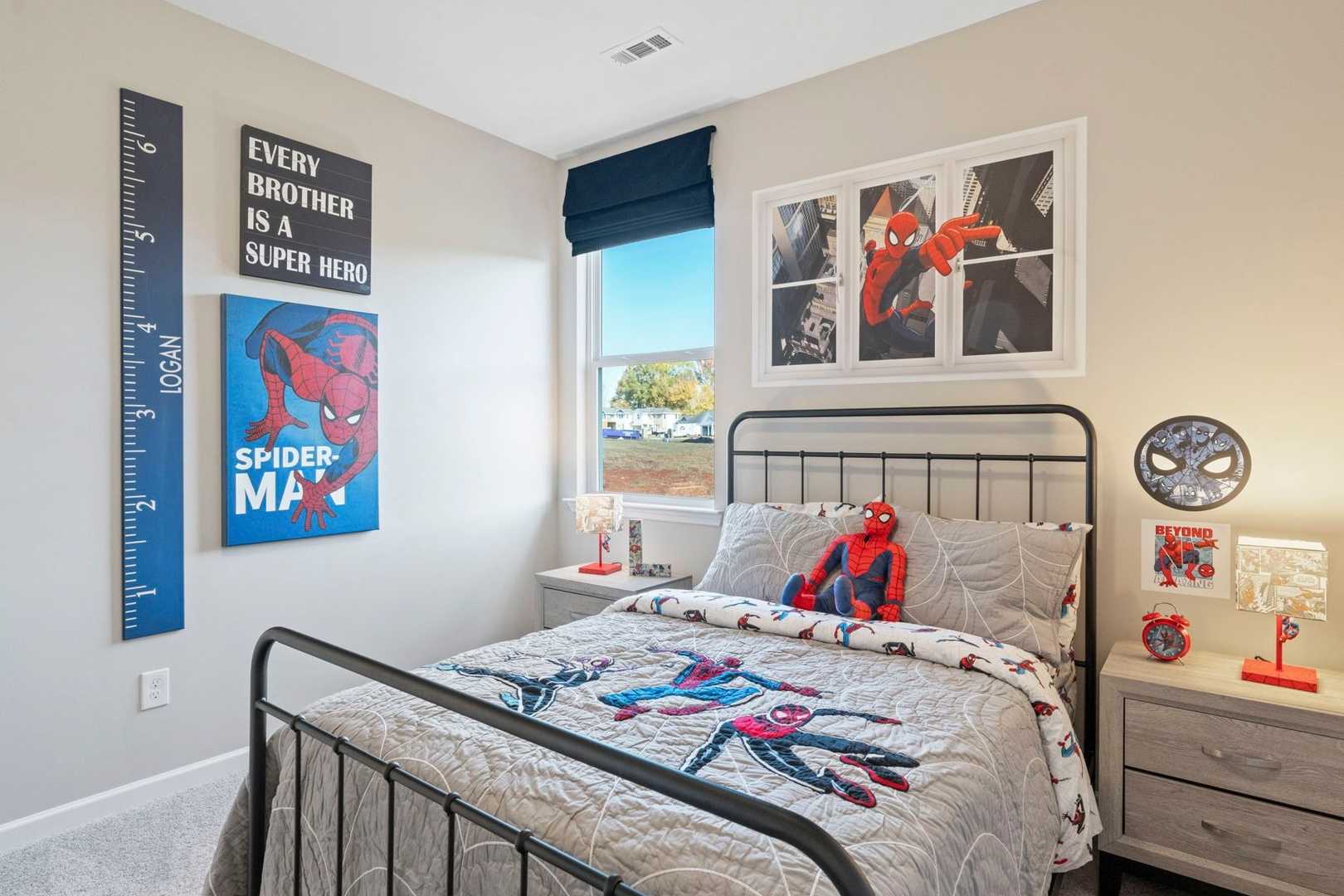 Cozy Spider-Man themed kids bedroom in The Phoenix home, featuring twin bed with gray bedding, posters, growth chart, and beige walls