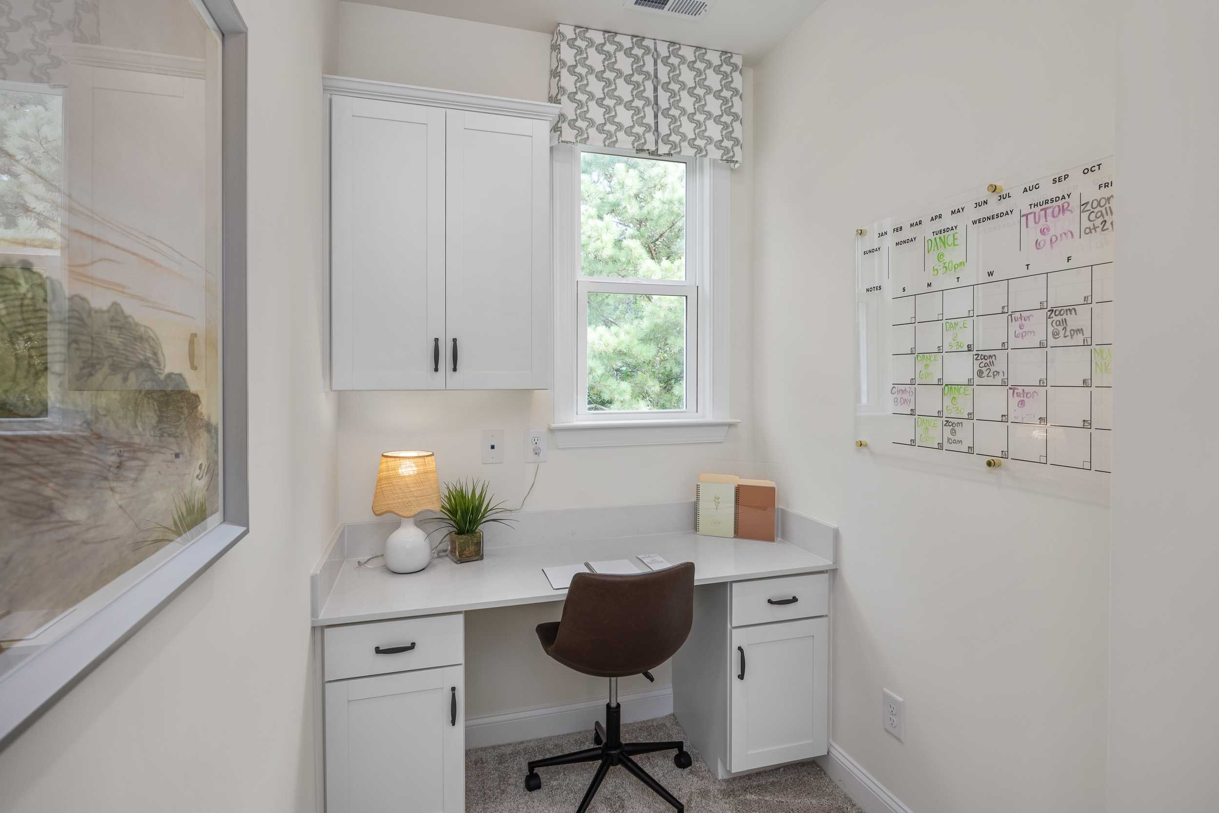Cozy home office at Laneridge Estates in Raleigh NC featuring white cabinetry, desk with leather chair, and window view