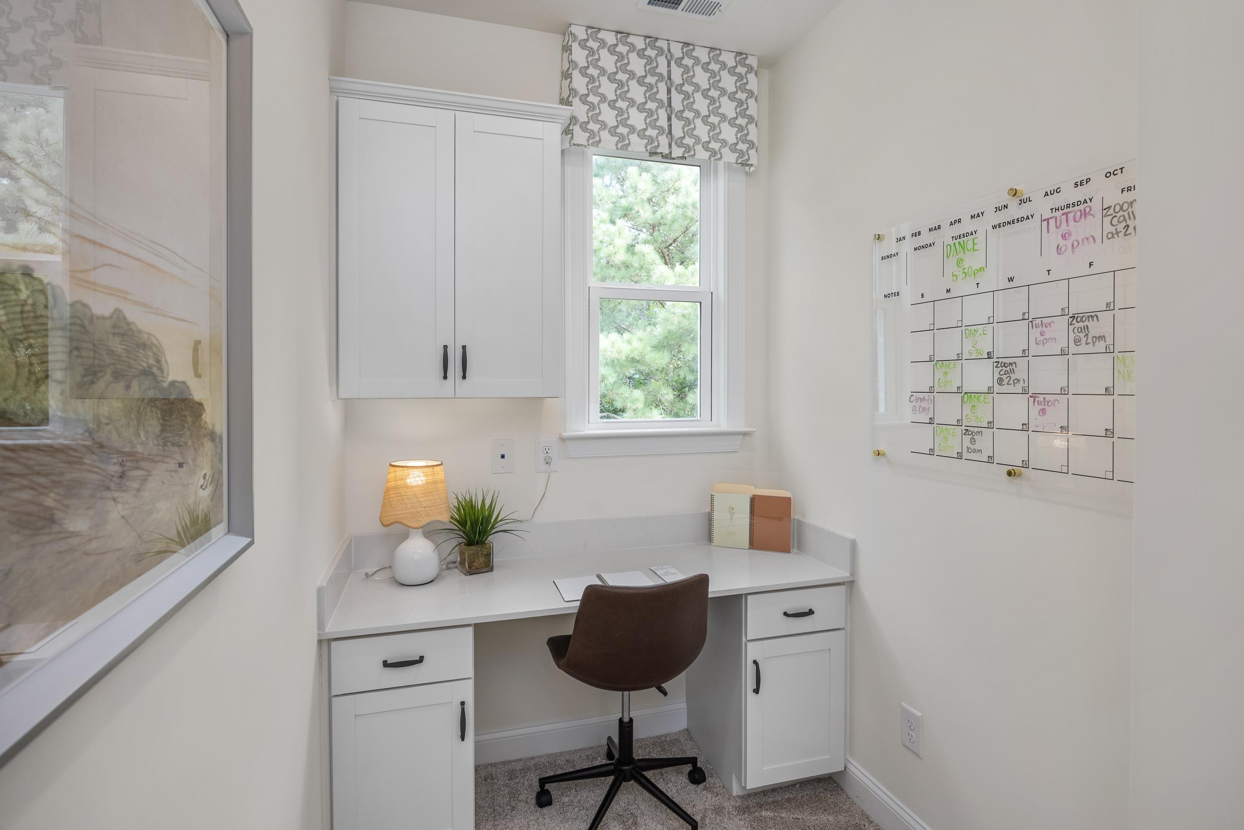 Cozy home office at Laneridge Estates in Raleigh NC featuring white cabinetry, desk with leather chair, and window view