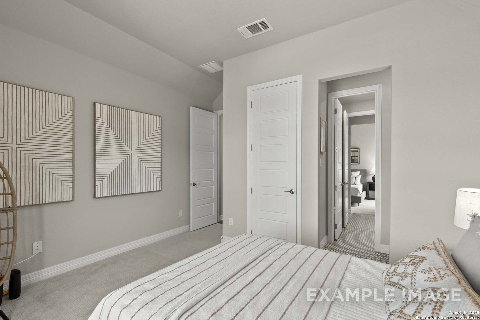 Cozy secondary bedroom with beige walls, abstract art, striped bedding, and rattan chair in Davidson Homes The Summerlin B, Castroville, Texas
