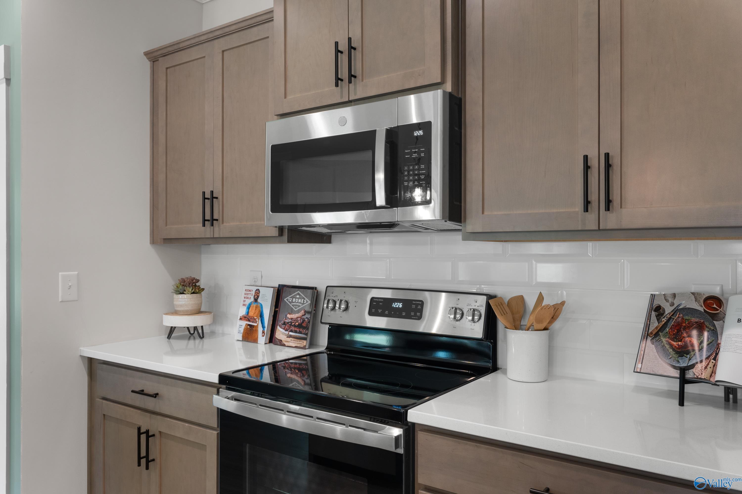 Modern kitchen with stainless steel appliances, white subway tile backsplash, and quartz countertops in The Franklin home.