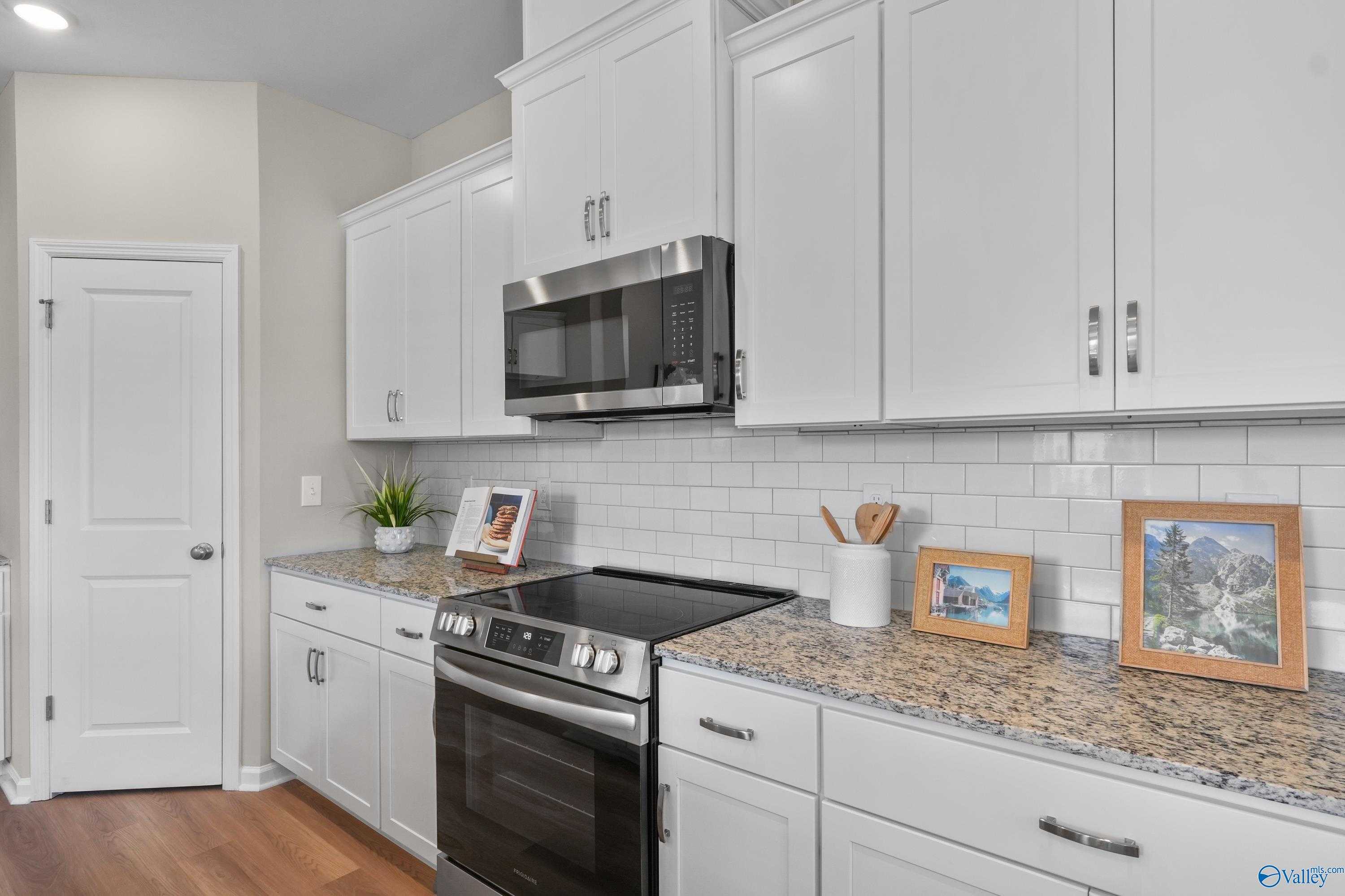 Bright kitchen with white shaker cabinets, stainless steel appliances, granite countertops in Evermore Homes Malibu, Madison Alabama